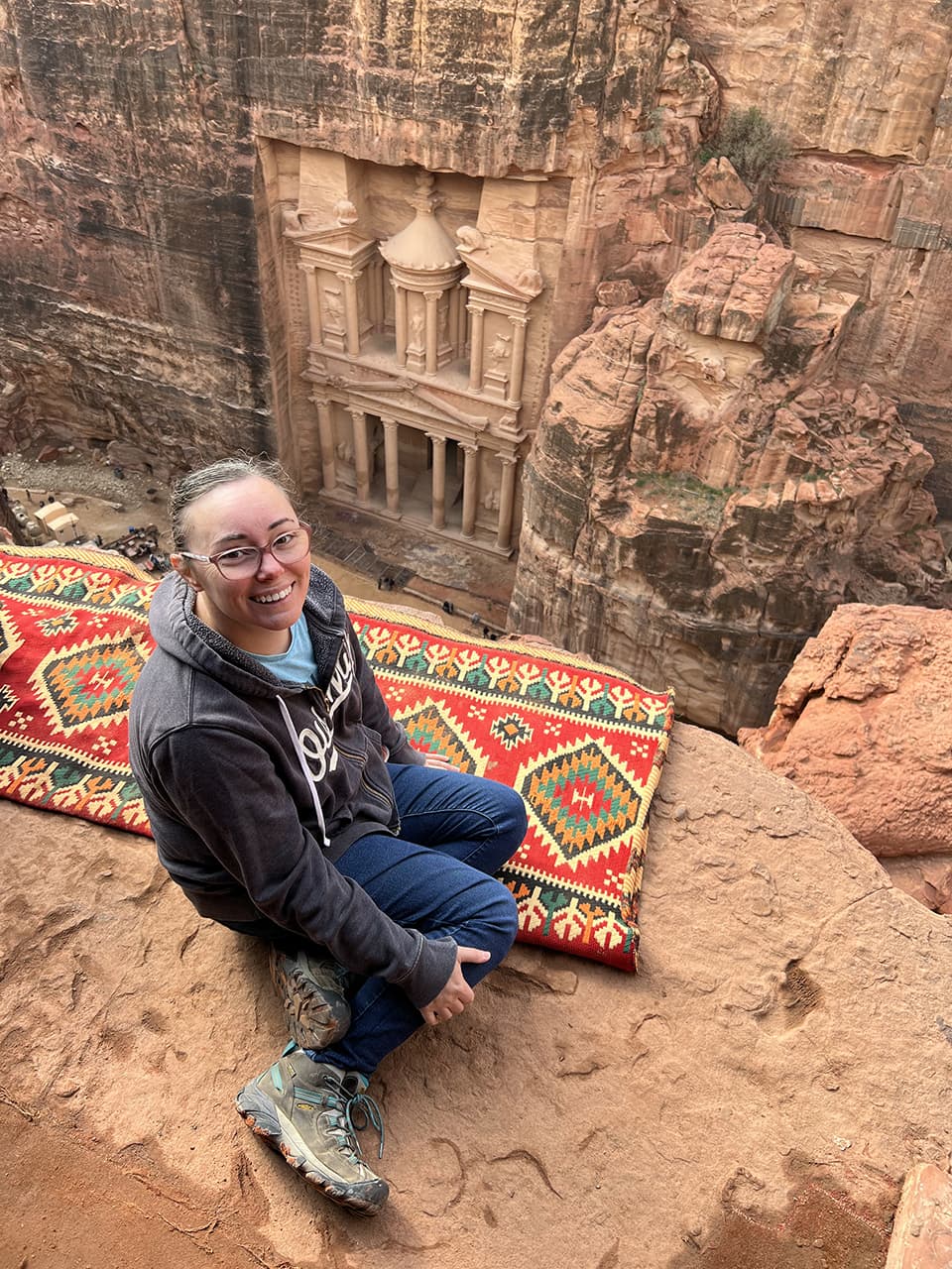 An advisor posing on top of a patterned rug and looking out towards ancient temples.