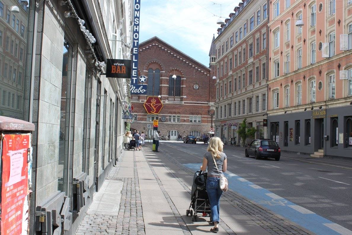 A picture of the advisor pushing a strolling down a city street with large buildings on each side.