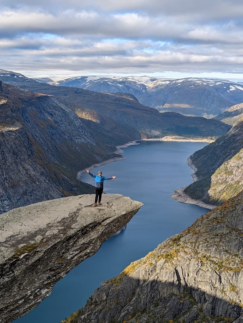 Advisor poses on a rock formation's edge over a snaking river the drifts into the distance on a sunny day.