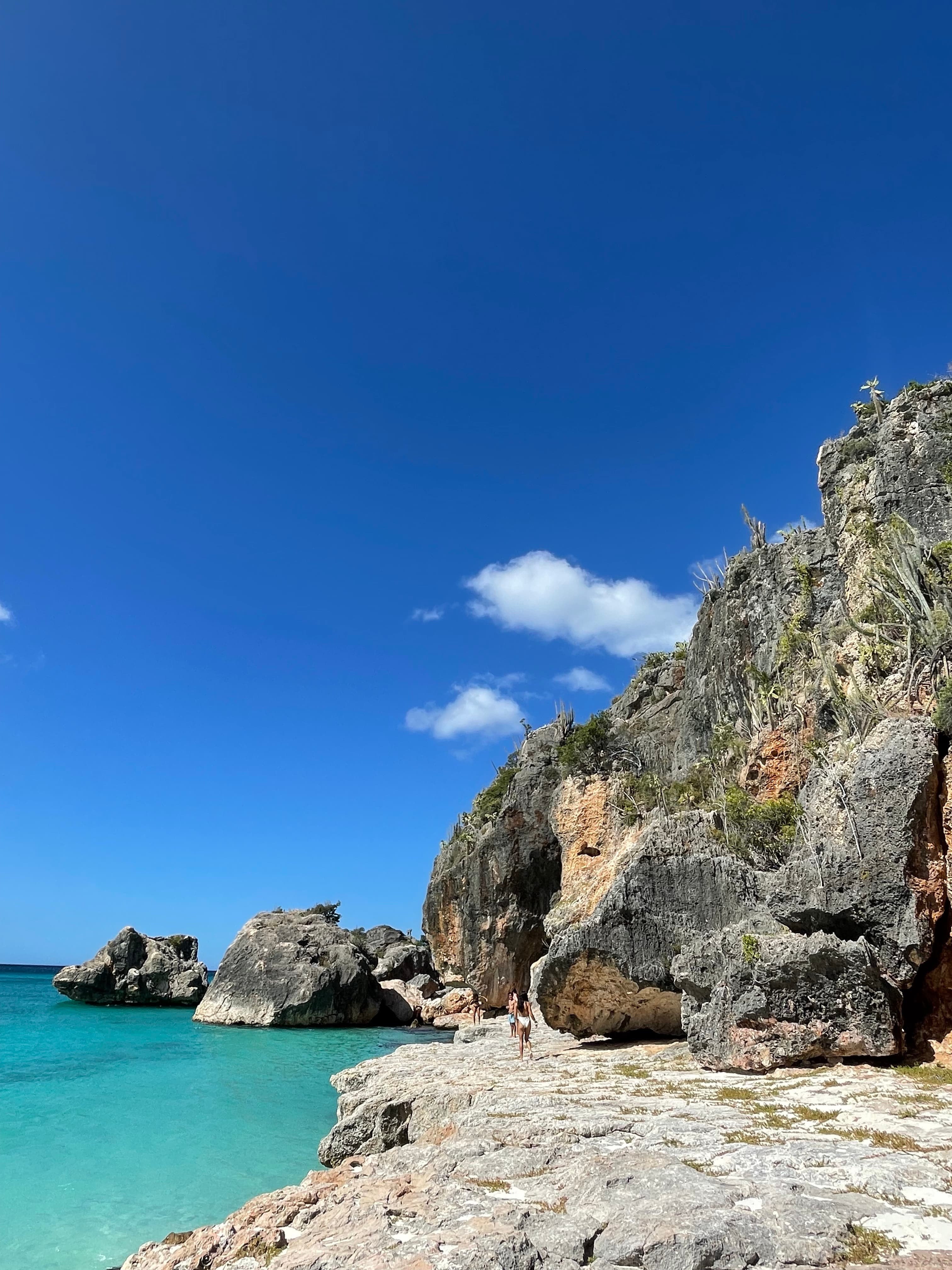 View of cliffs along a bright turquoise sea under clear skies