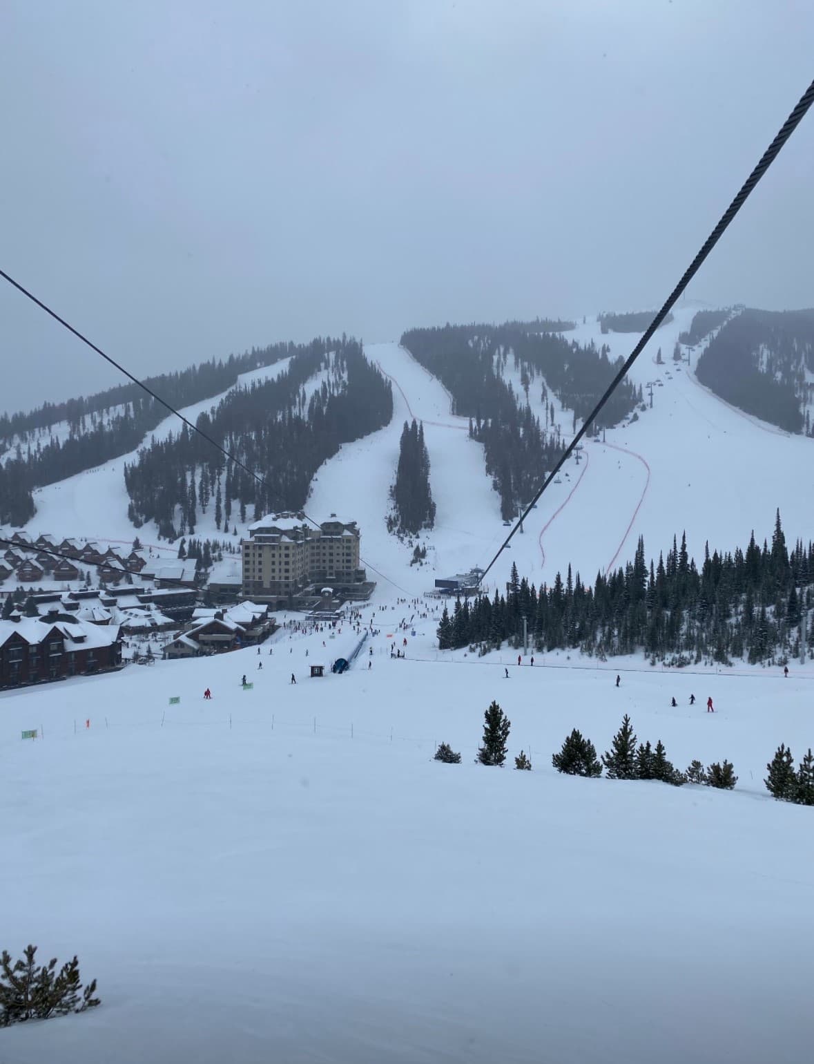 A snowy ski mountain on a cloudy day as the lift scaled the hillside.