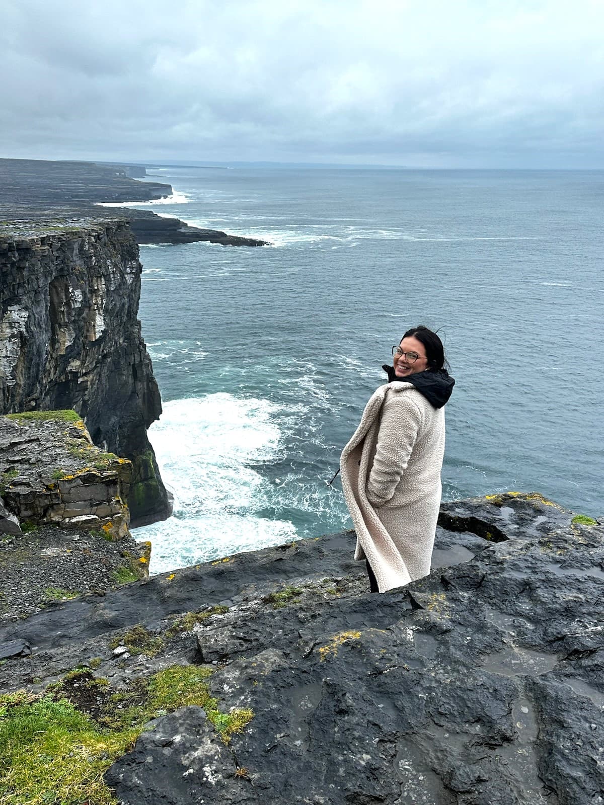 Advisor poses cliffside as waves crash against the rocky shore below.