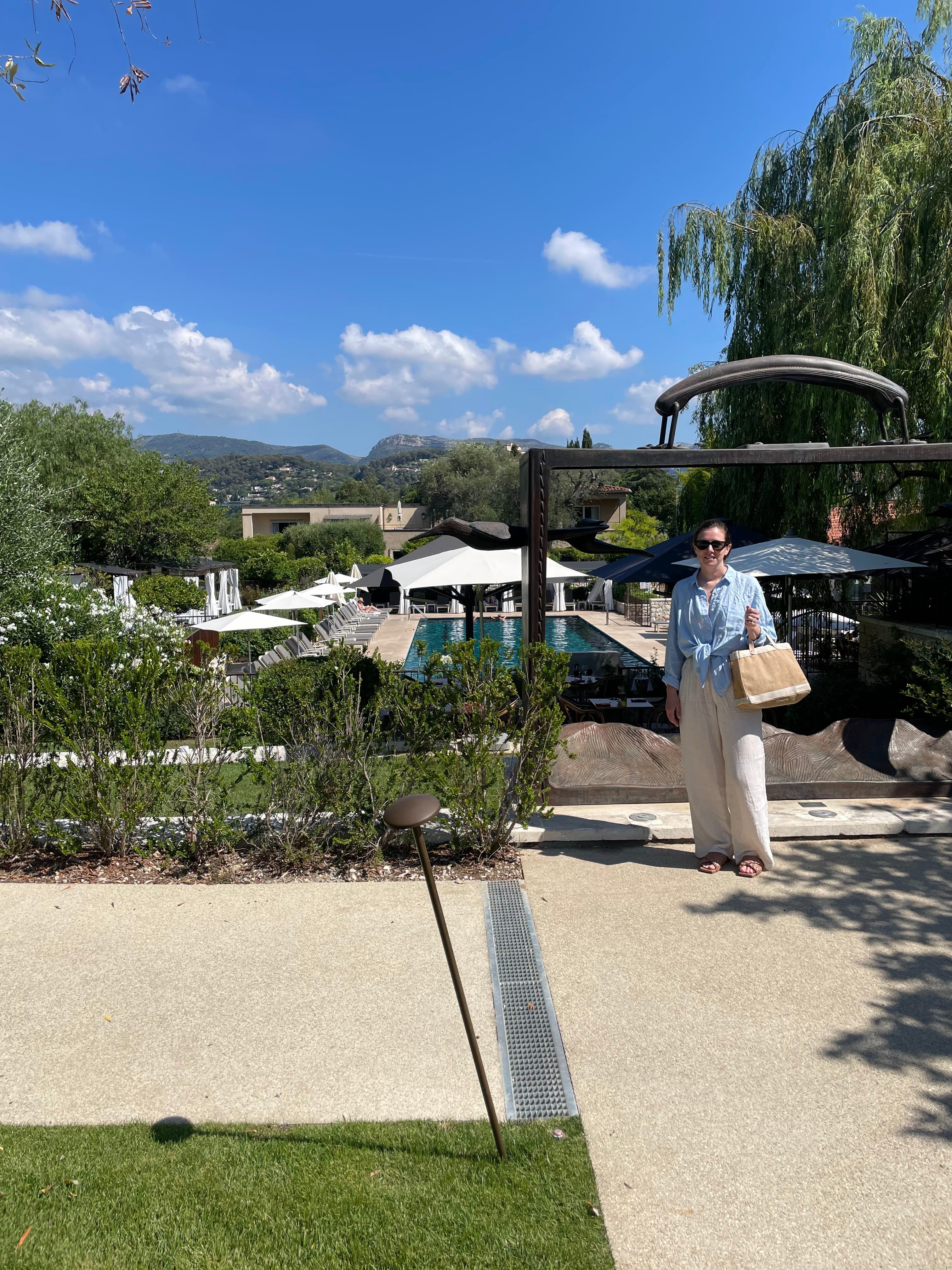 Advisor posing for an image with a pool in the distance on sunny day.