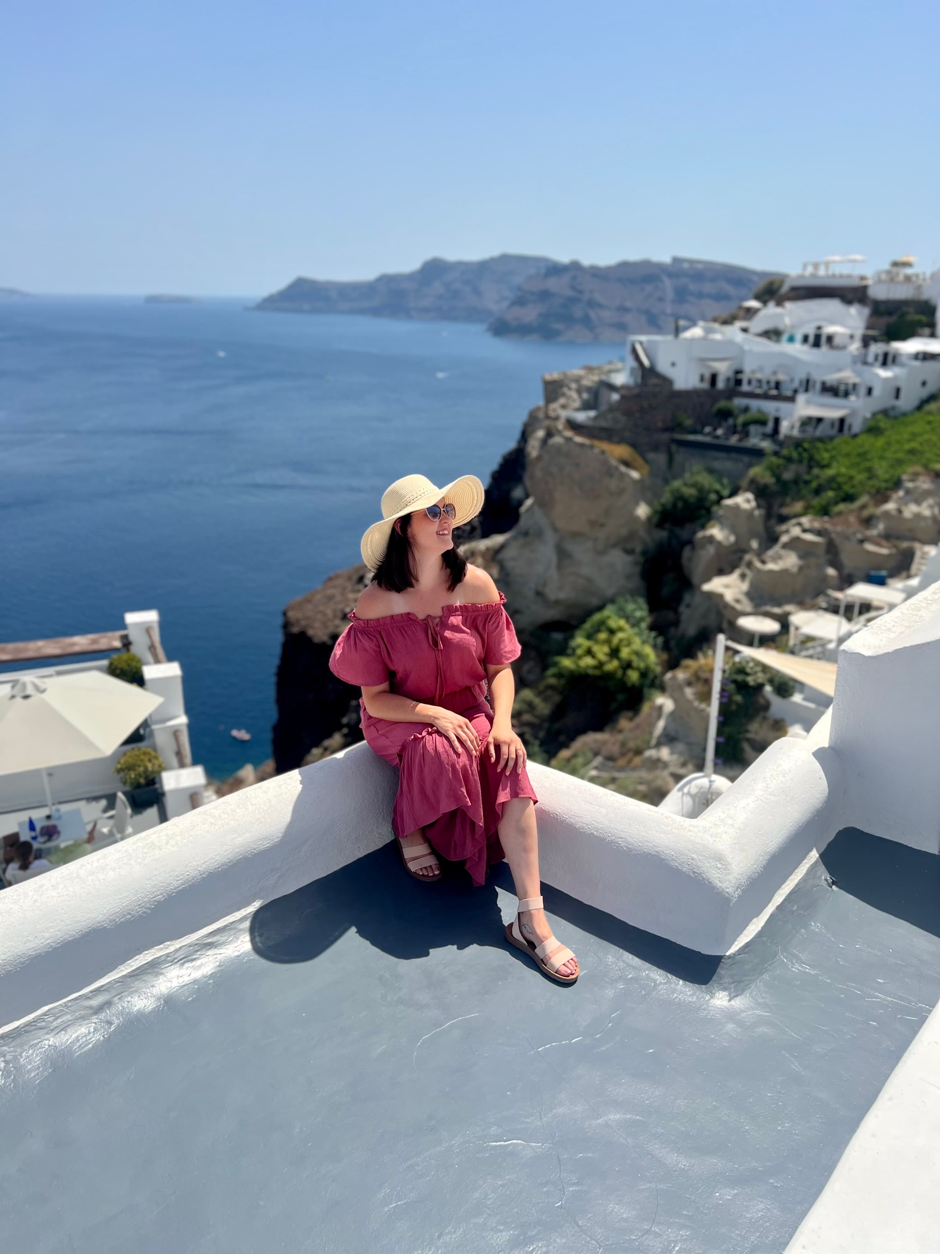 Advisor in a pink dress sitting on a rooftop overlooking the sea on a sunny day