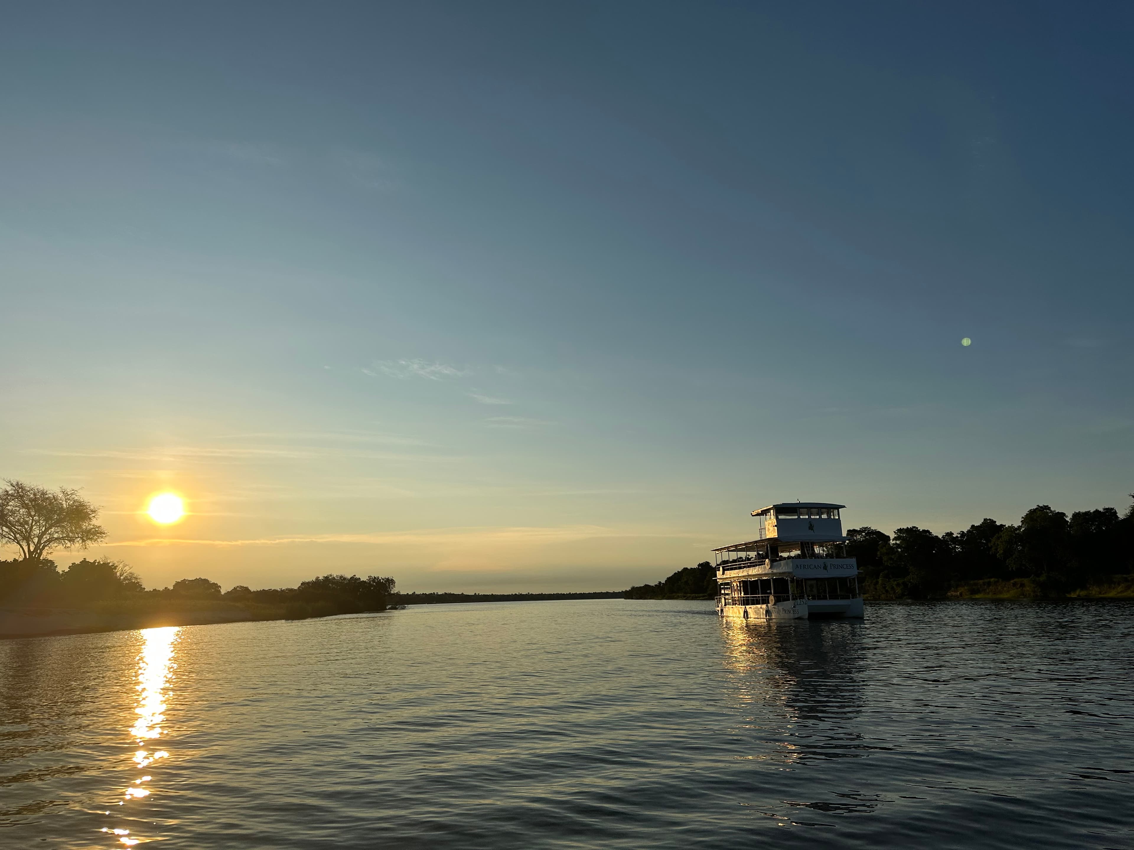A view of a boat on a lake with the sun setting in the background.