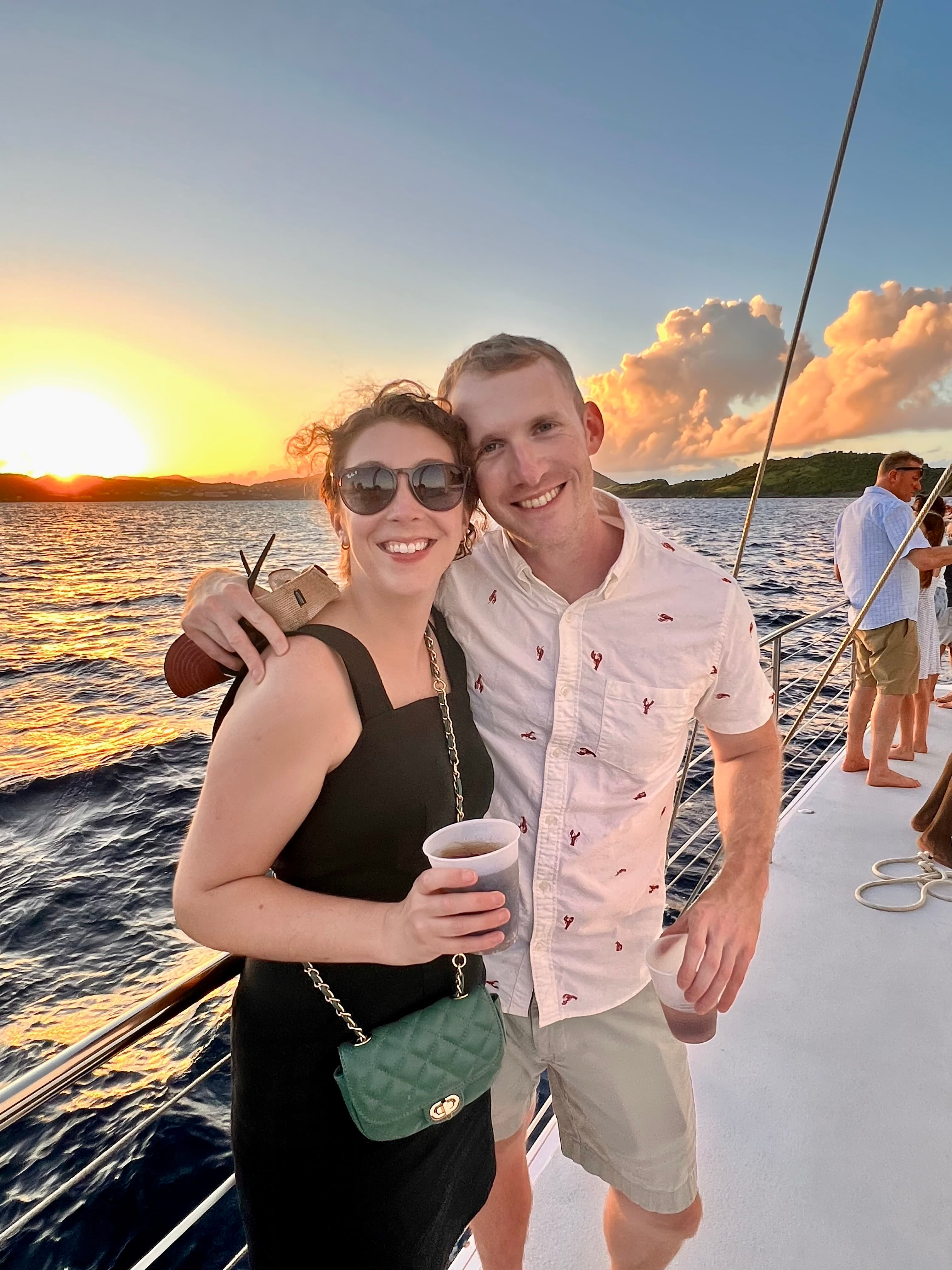 A couple poses together on a boat during sunset.