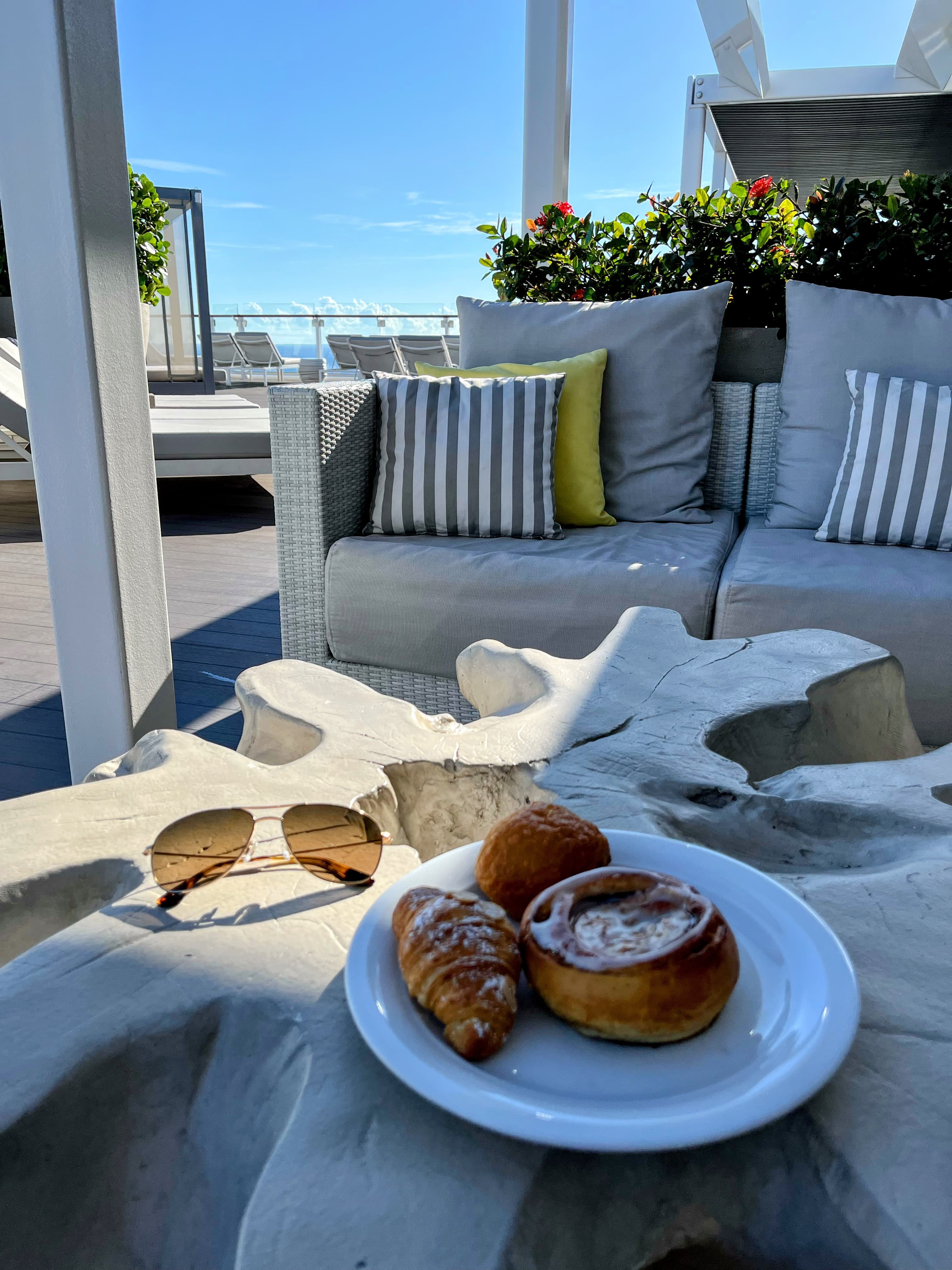 View of three small pastries on a white plate on an outdoor table