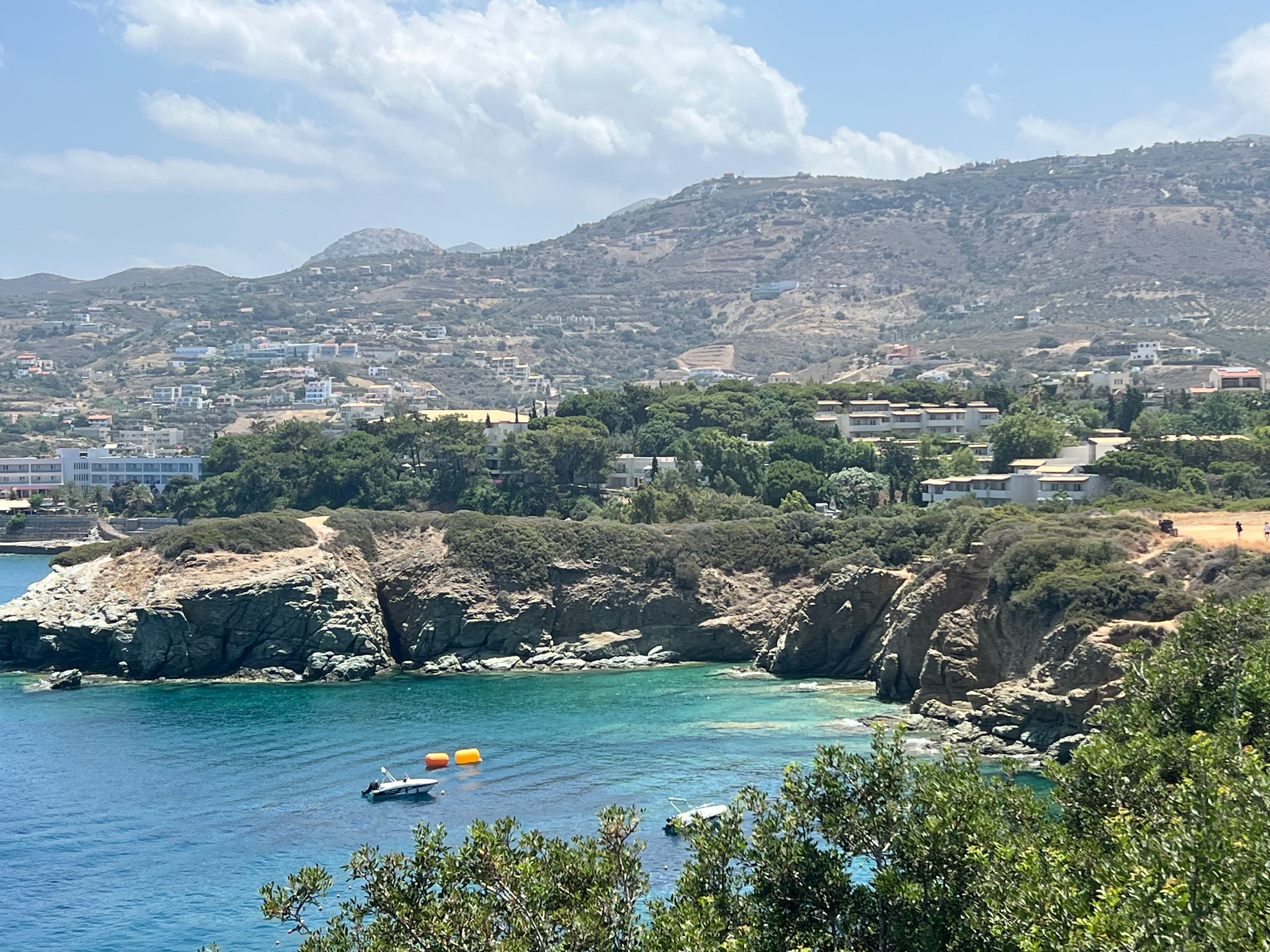 Aerial view of a small secluded bay with a small boat docked offshore on a sunny day