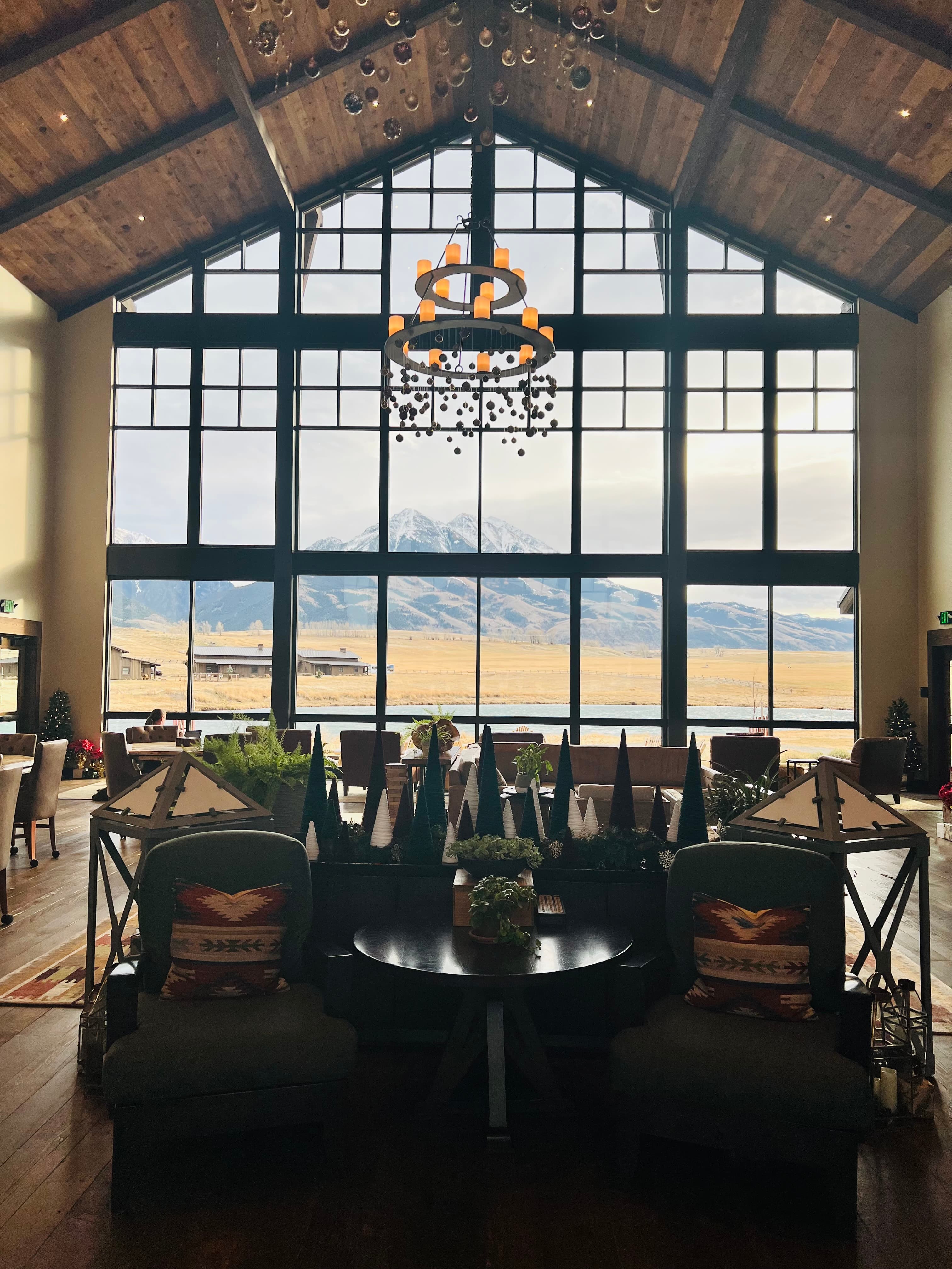 Interior view of an empty restaurant with large glass windows in back featuring views of mountains in the distance