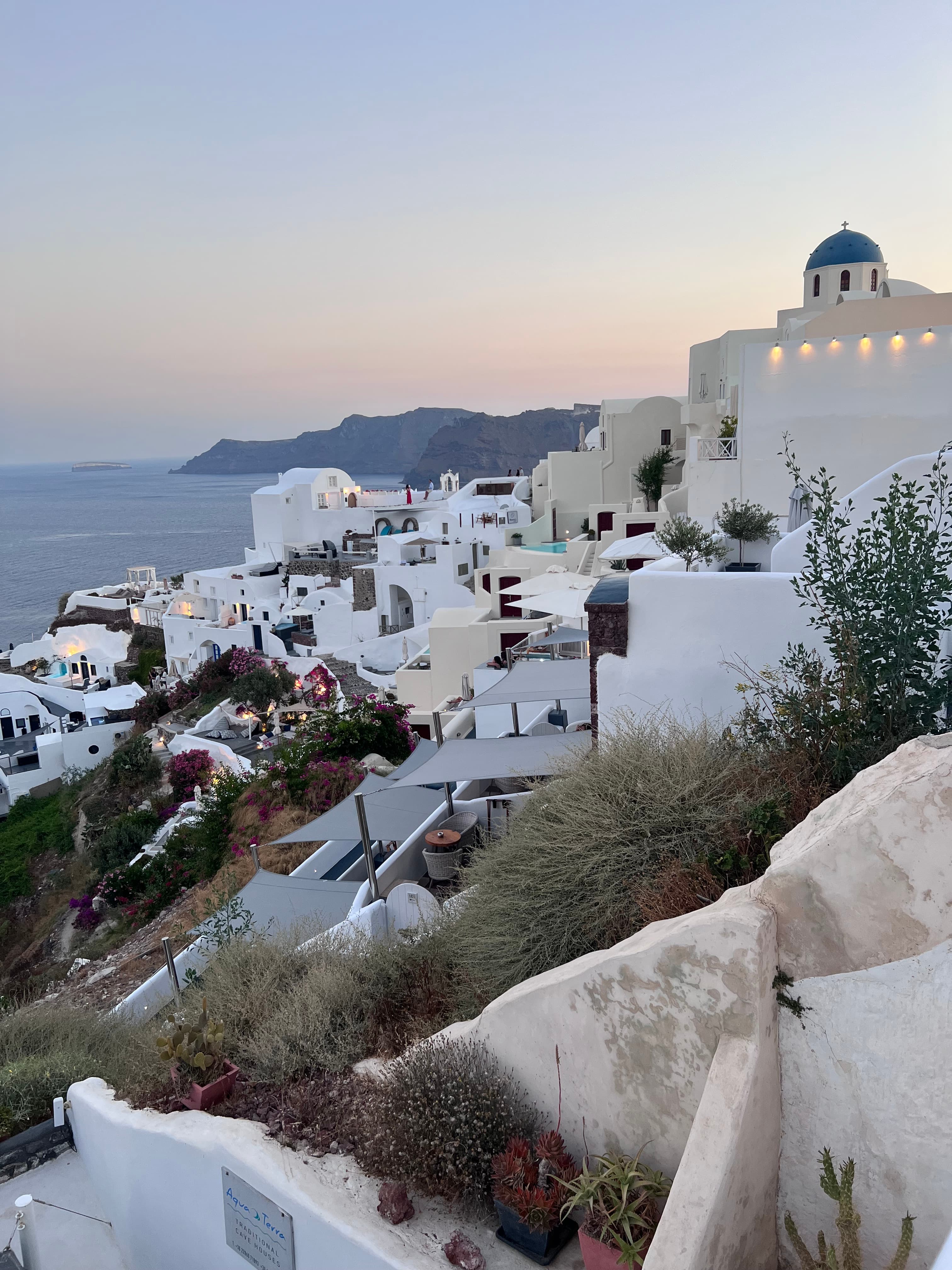View of white buildings stretching to the coast in Santorini at sunset