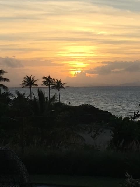 View of the sun setting behind clouds over the sea