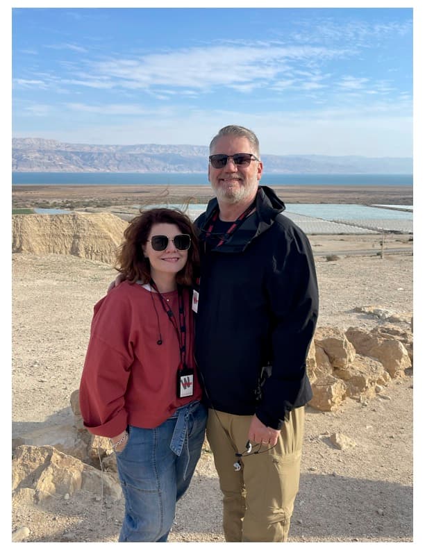 Advisor and partner smiling side by side with the sea visible in the distance on a sunny day