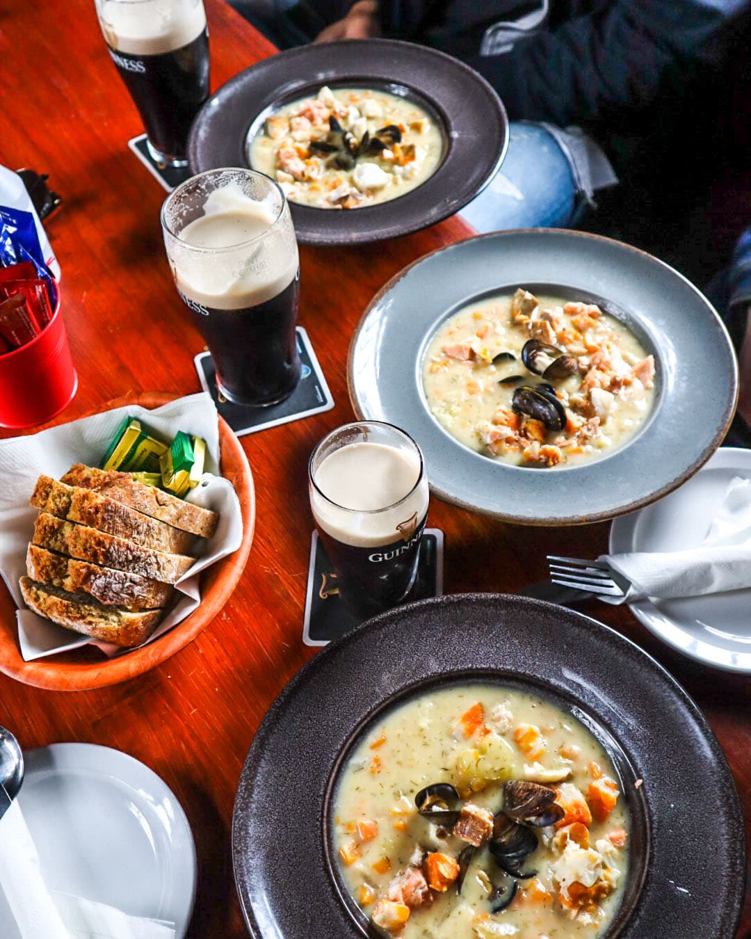 View of three bowls of soup and bread with pints of Guinness on a restaurant table