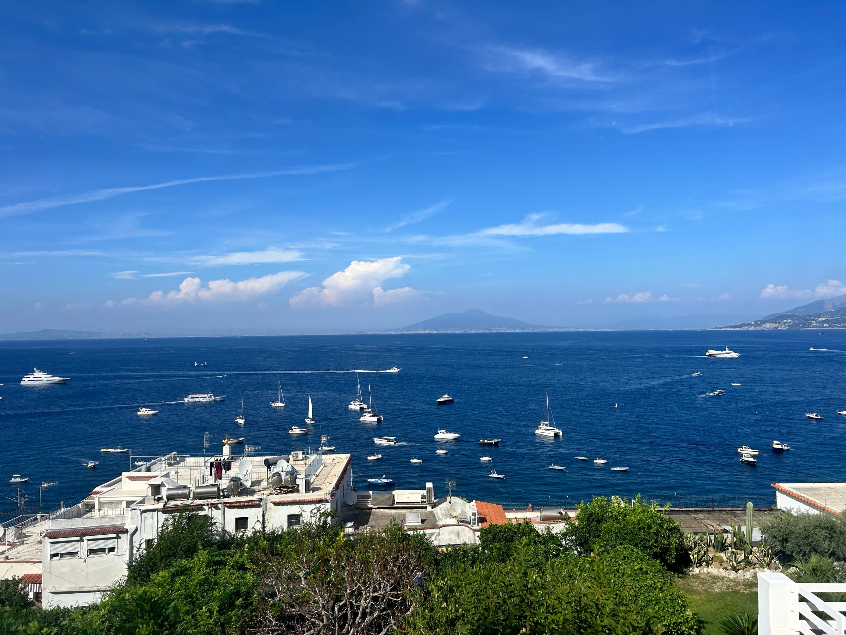 Aerial view of a harbor with boats docked offshore on a sunny day