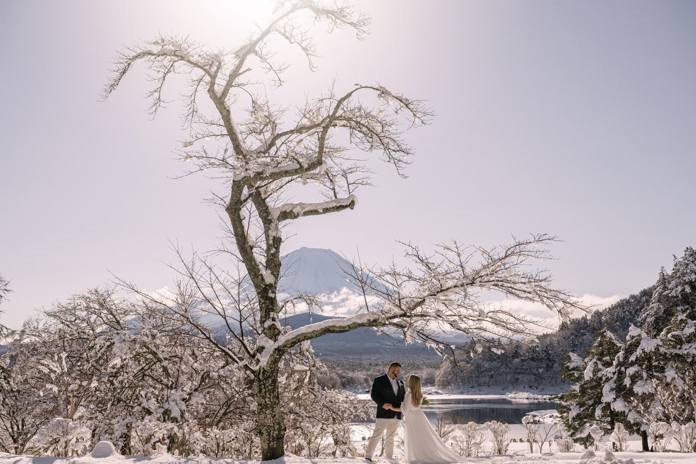 View of advisor and partner standing amidst a snowy environment with a volcano visible in the distance
