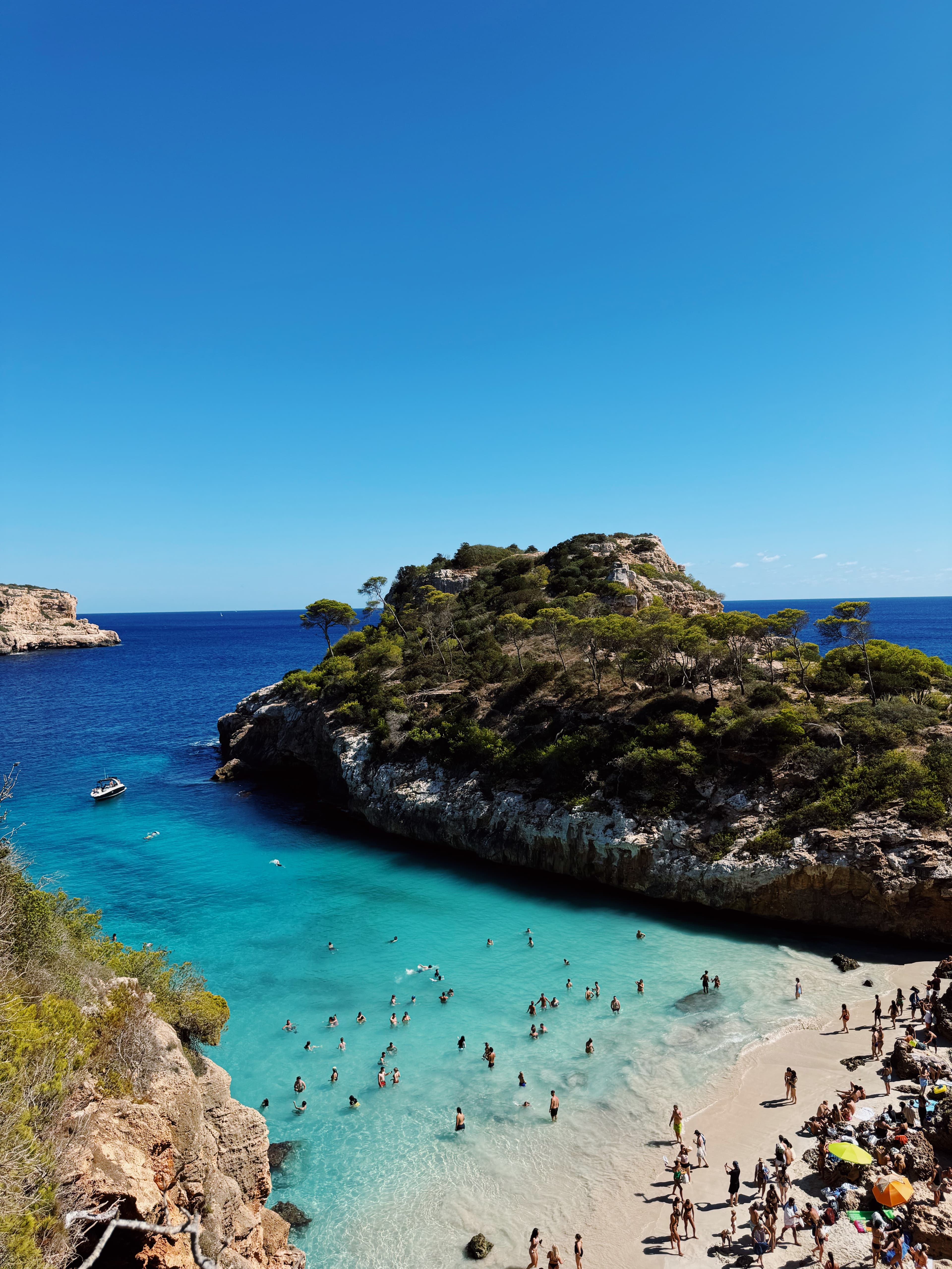View of a beautiful white sand beach and clear water with sunbathers enjoying a sunny day