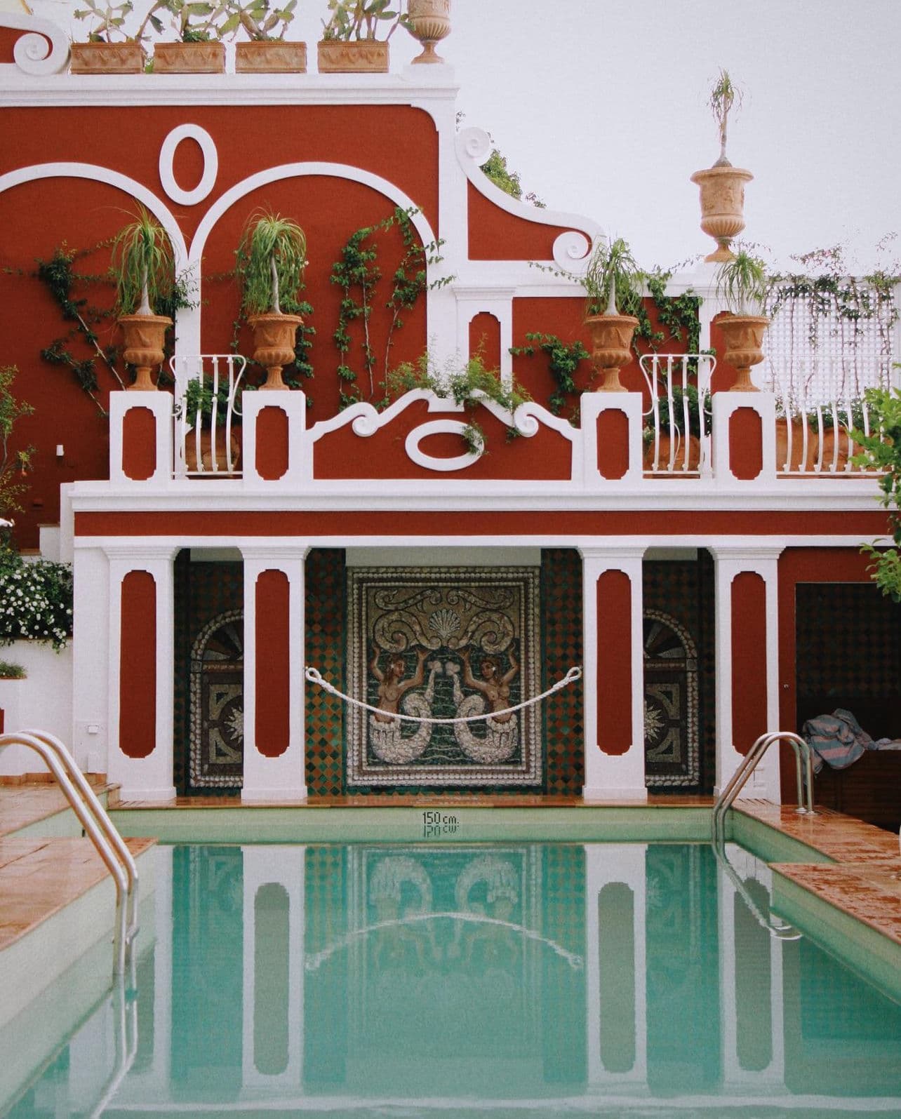 View of a resort pool with red and white walls and mosaic decoration