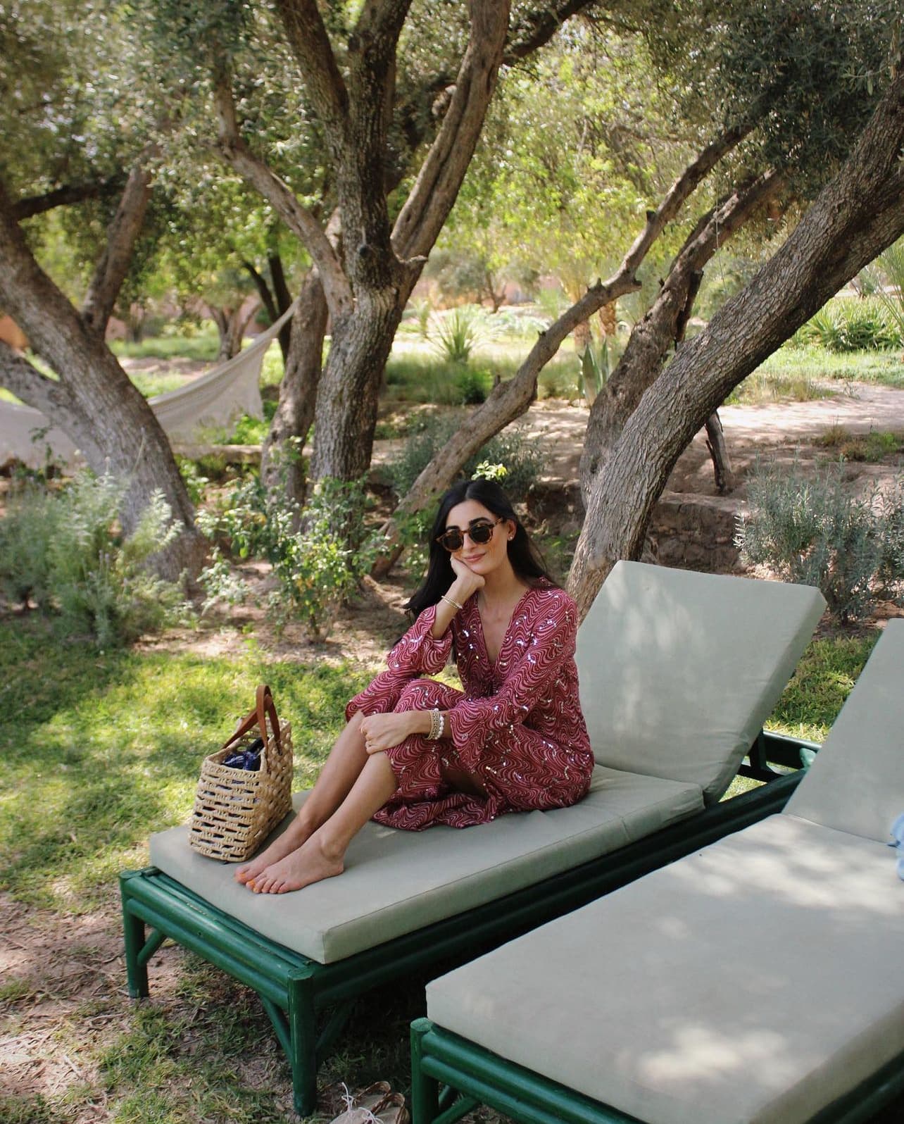 Advisor in a long dress sitting on a white chaise lounge under a tree on a sunny day
