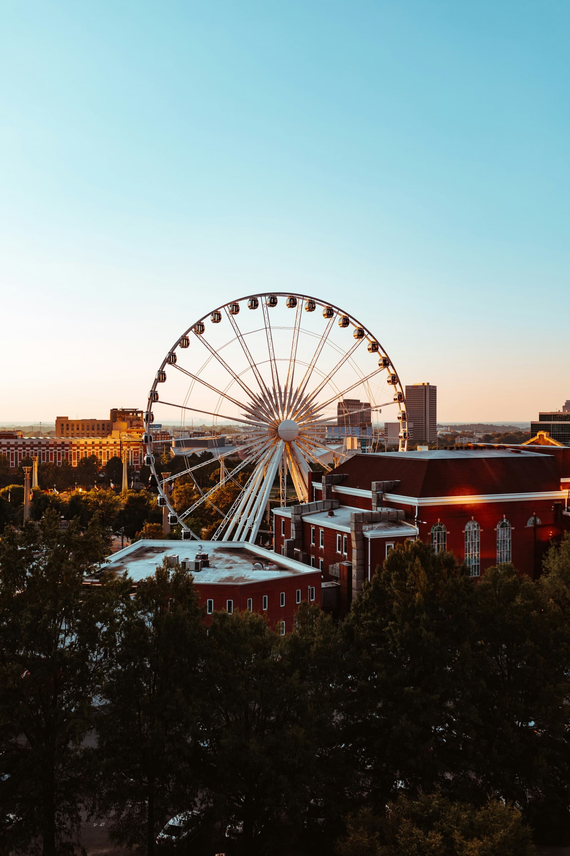 A view of a carnival and a ferris wheel at sunset.
