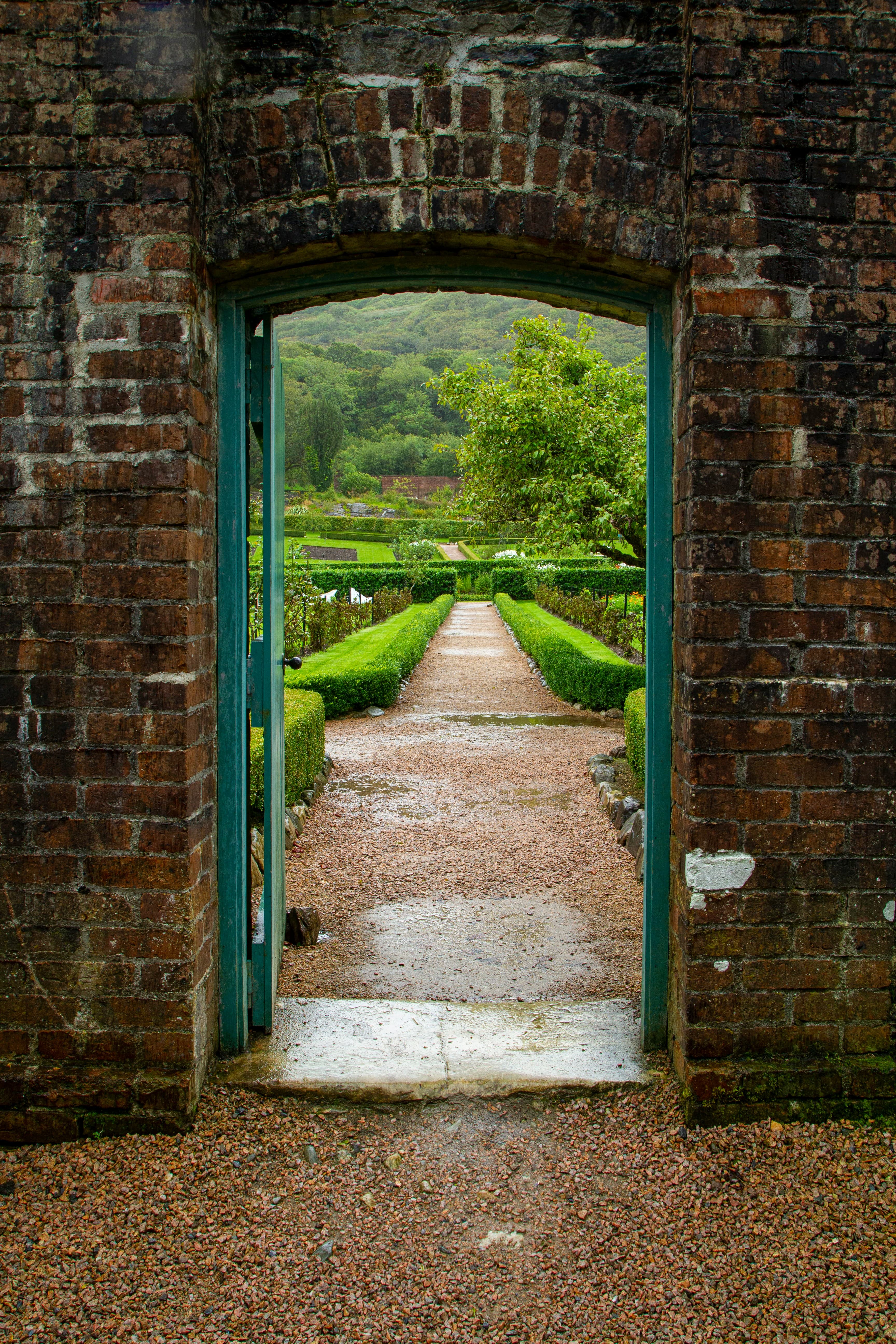 A door in a brick wall leading to a manicured garden, which you might see on an Ireland honeymoon.