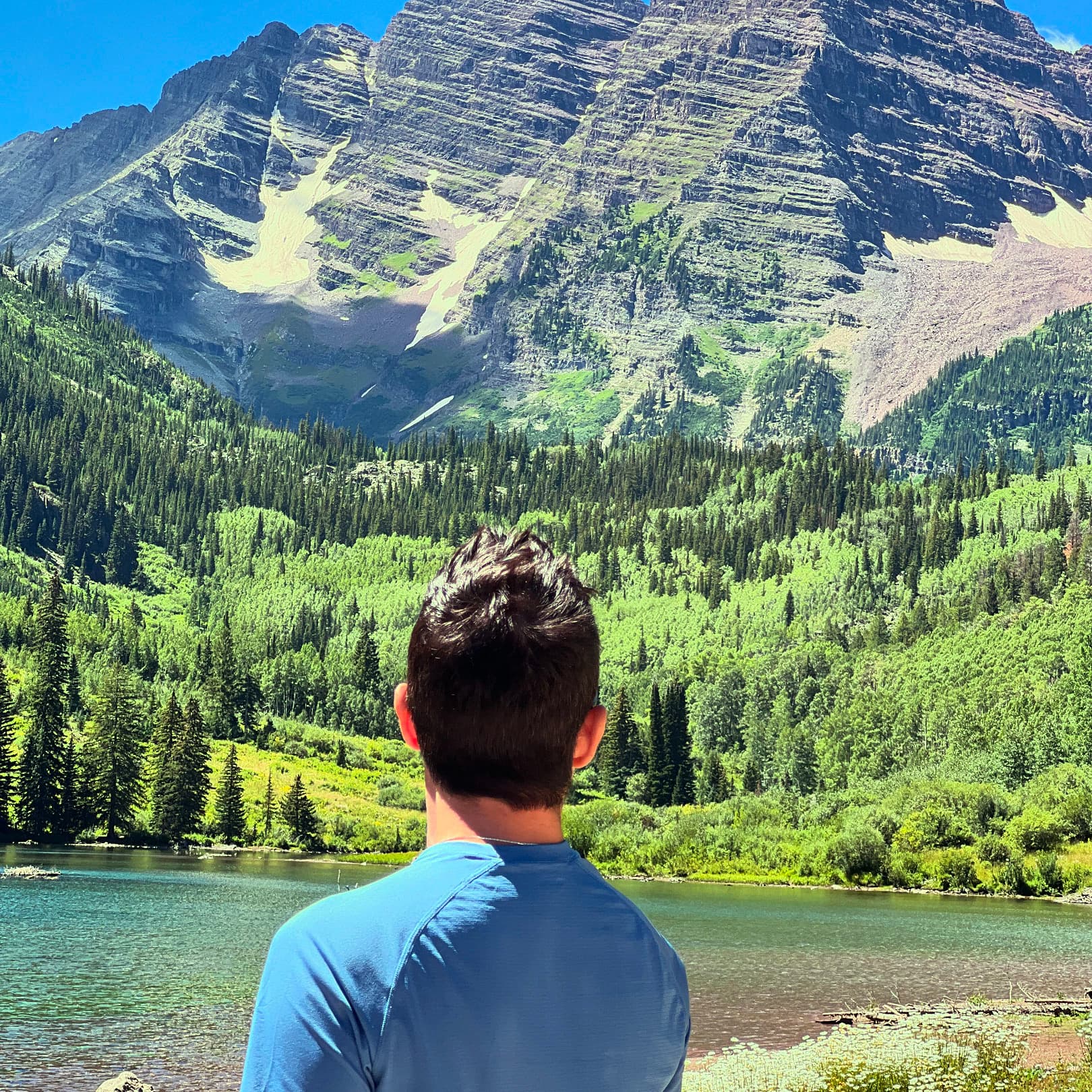 A man looking over a lake and a mountain.