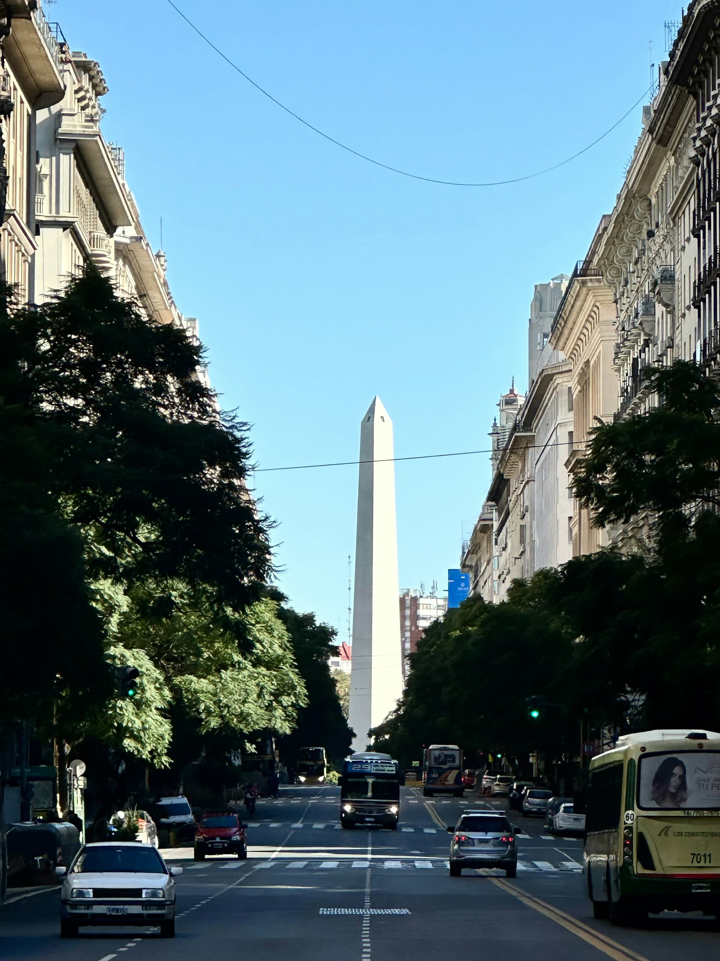 A road through a city street with a tall monument at the end during the daytime