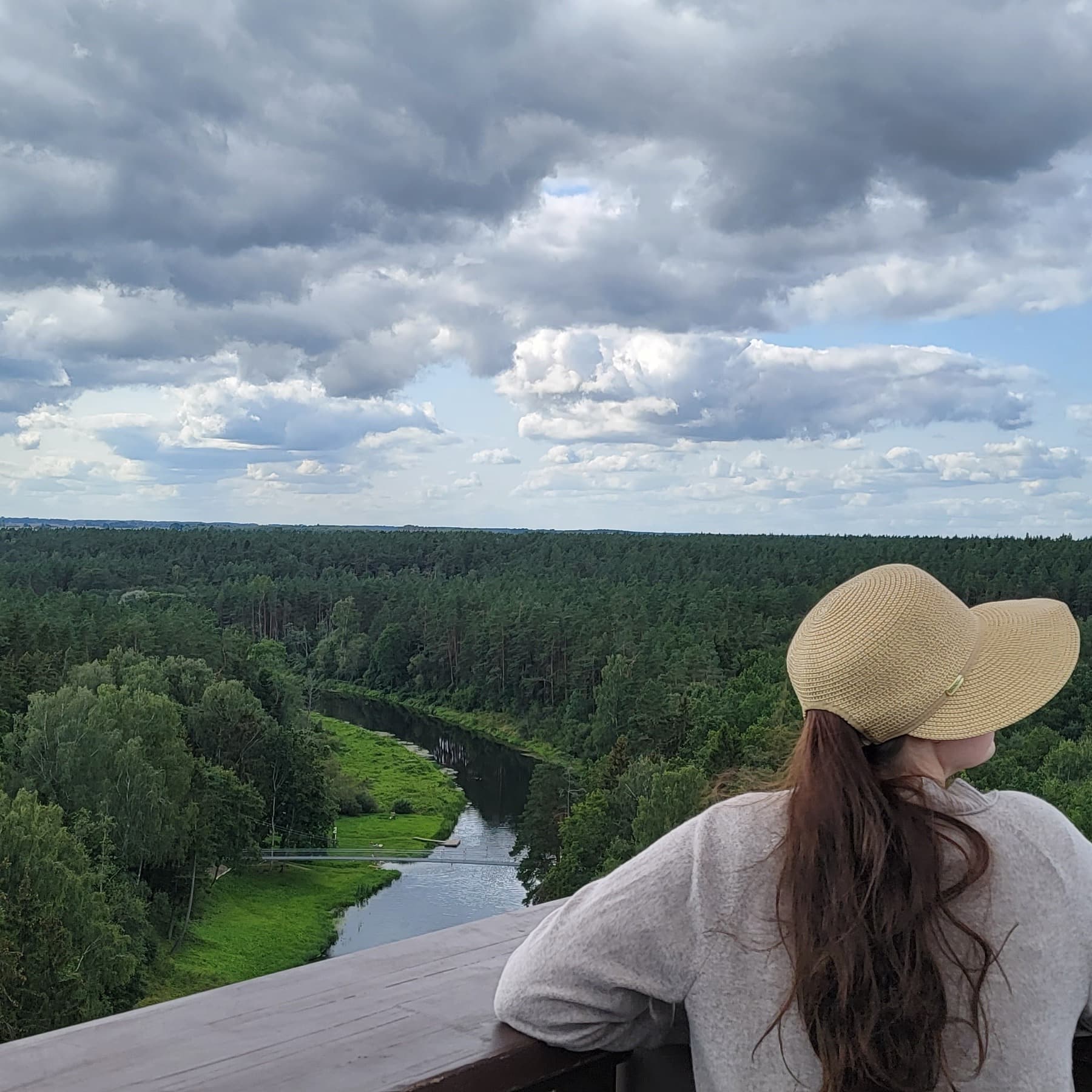 A woman overlooking a view of river surrounded by trees.