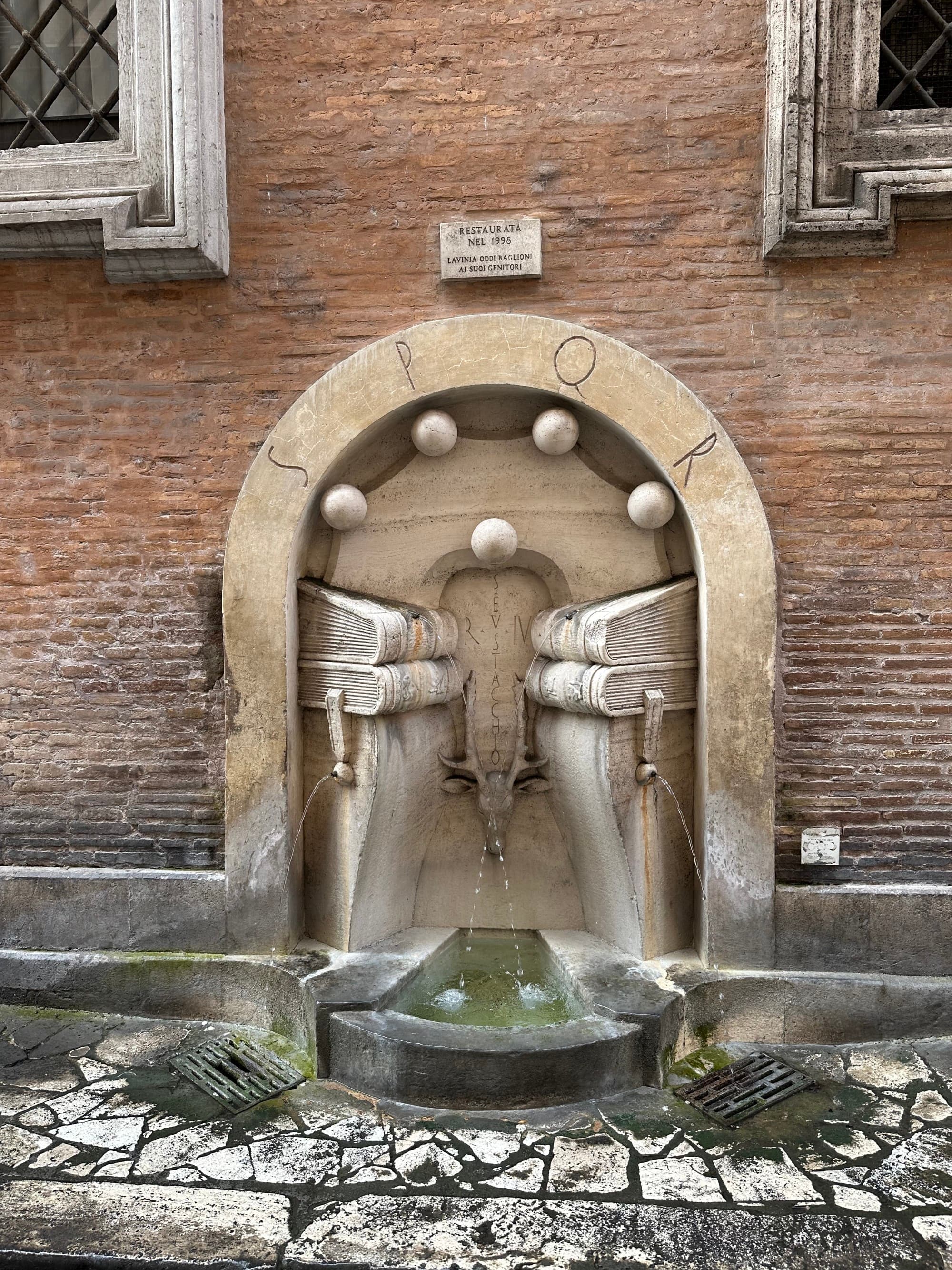 Rome's Fountain of the Books, with water flowing from carved books in a fountain on the side of a building.