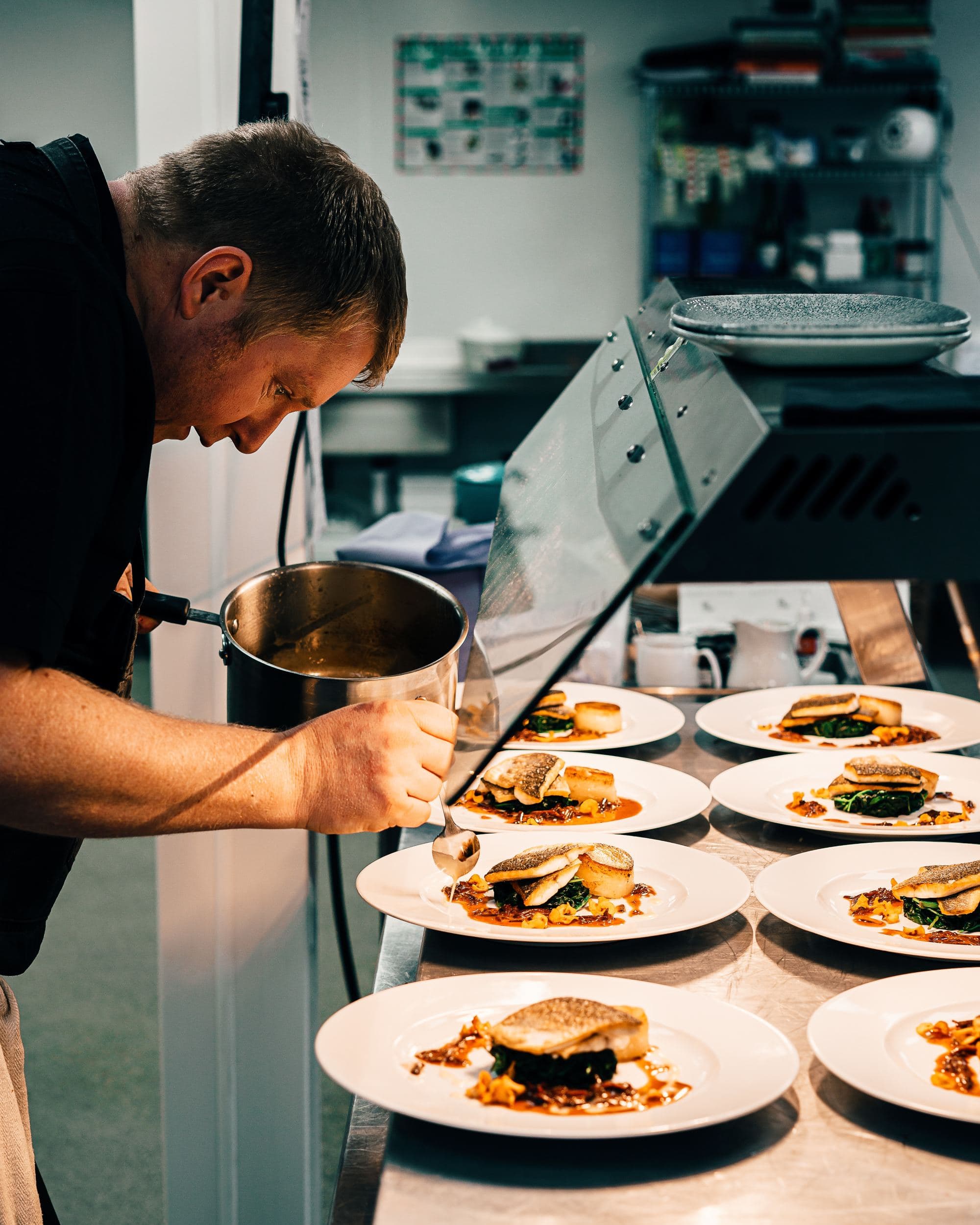 A picture of a chef garnishing food served on plates.