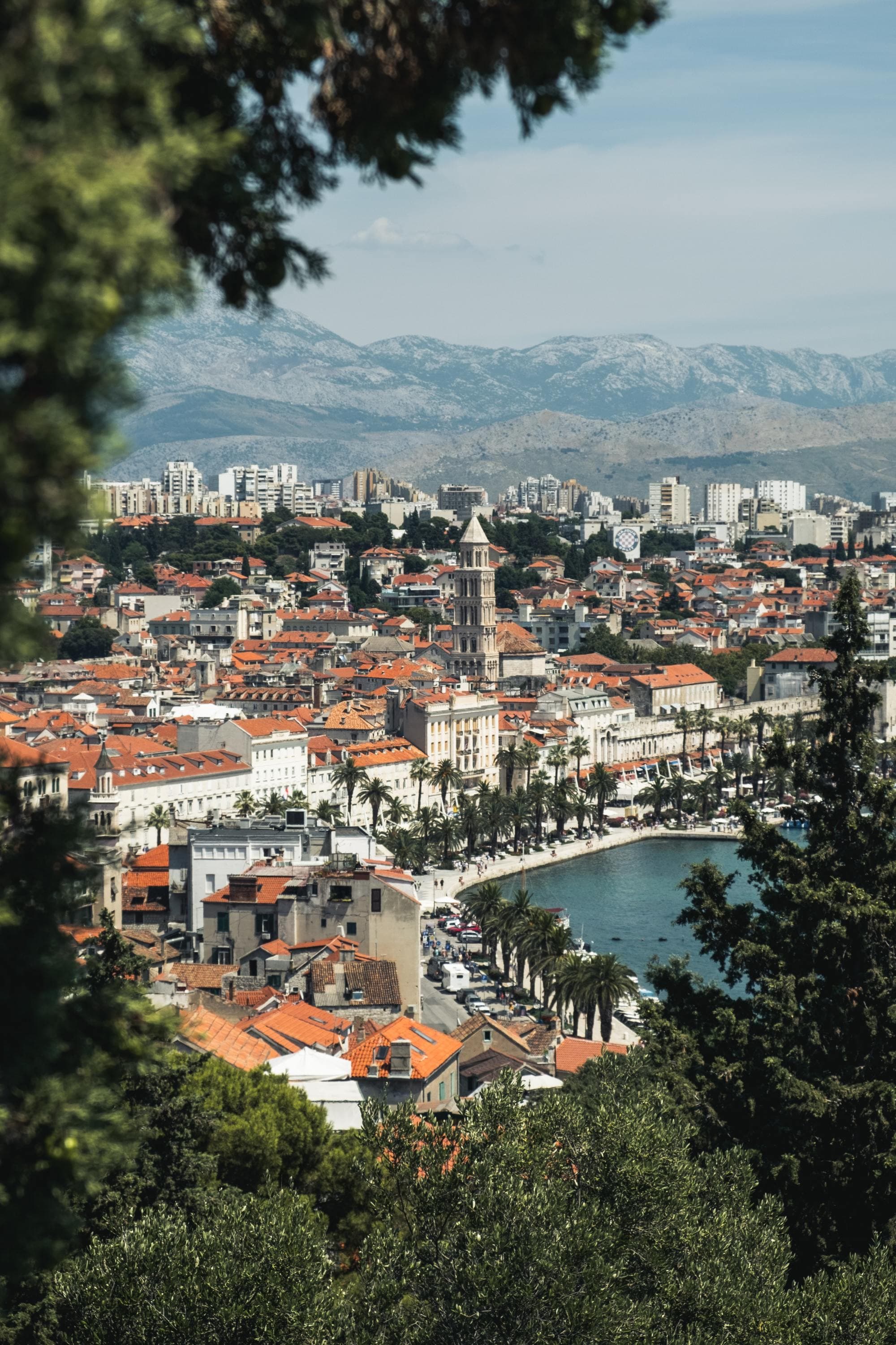 view from above an old city with white buildings and orange rooftops and mountains in the background