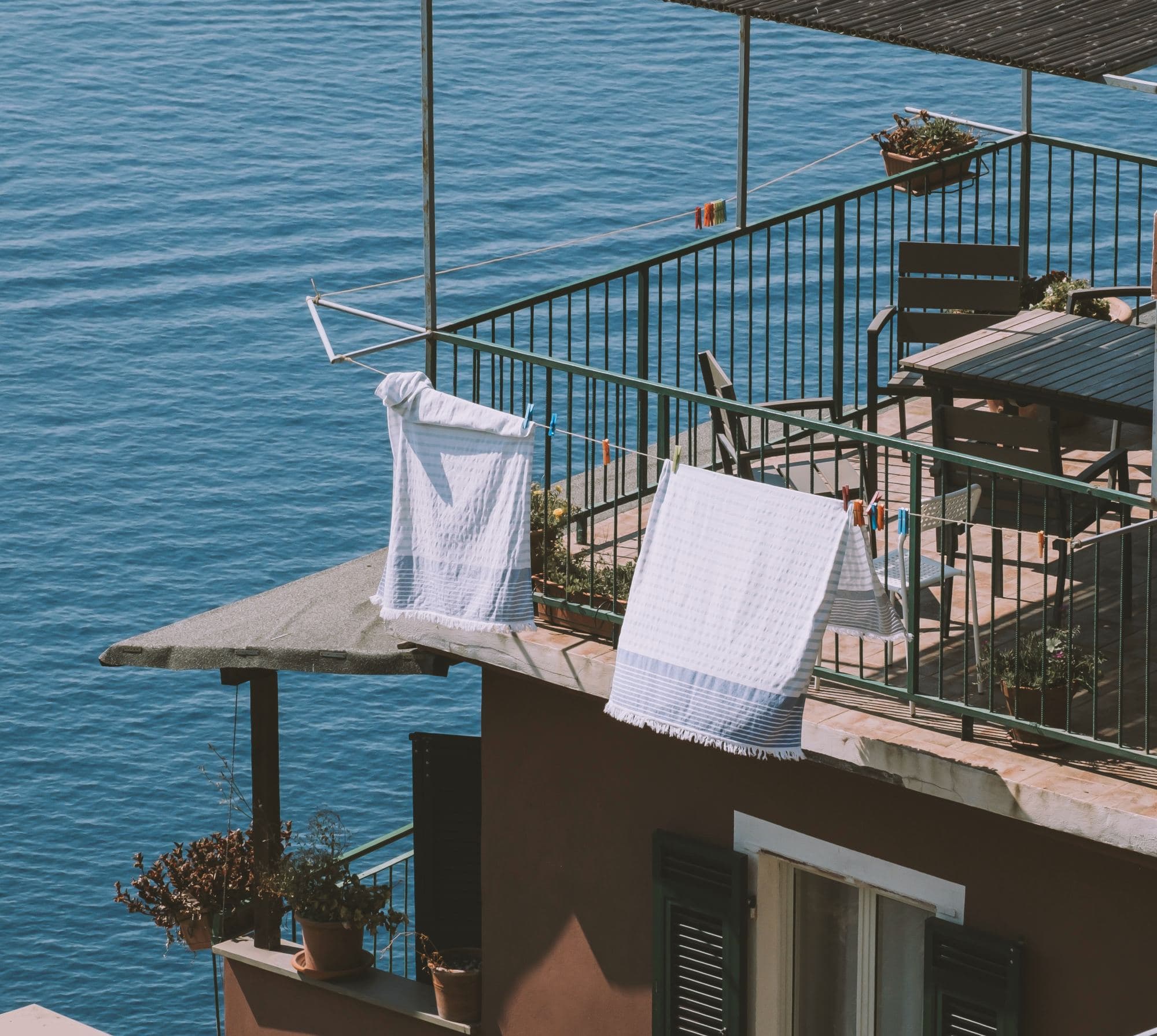 Clothes hanging out to dry on a balcony over a body of water.