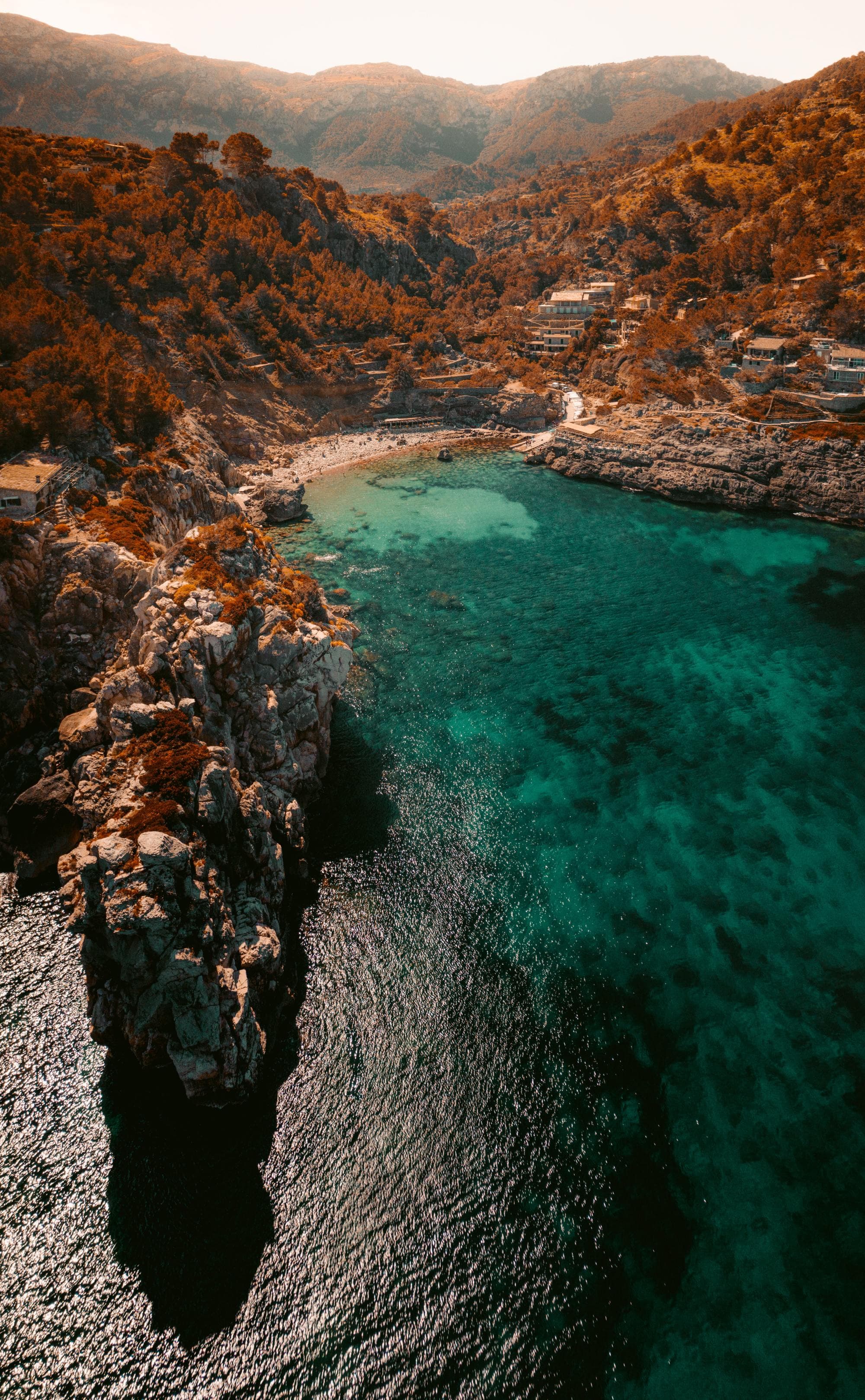 aerial view of vivid blue green waters of an island coast with clifss and mountainrange