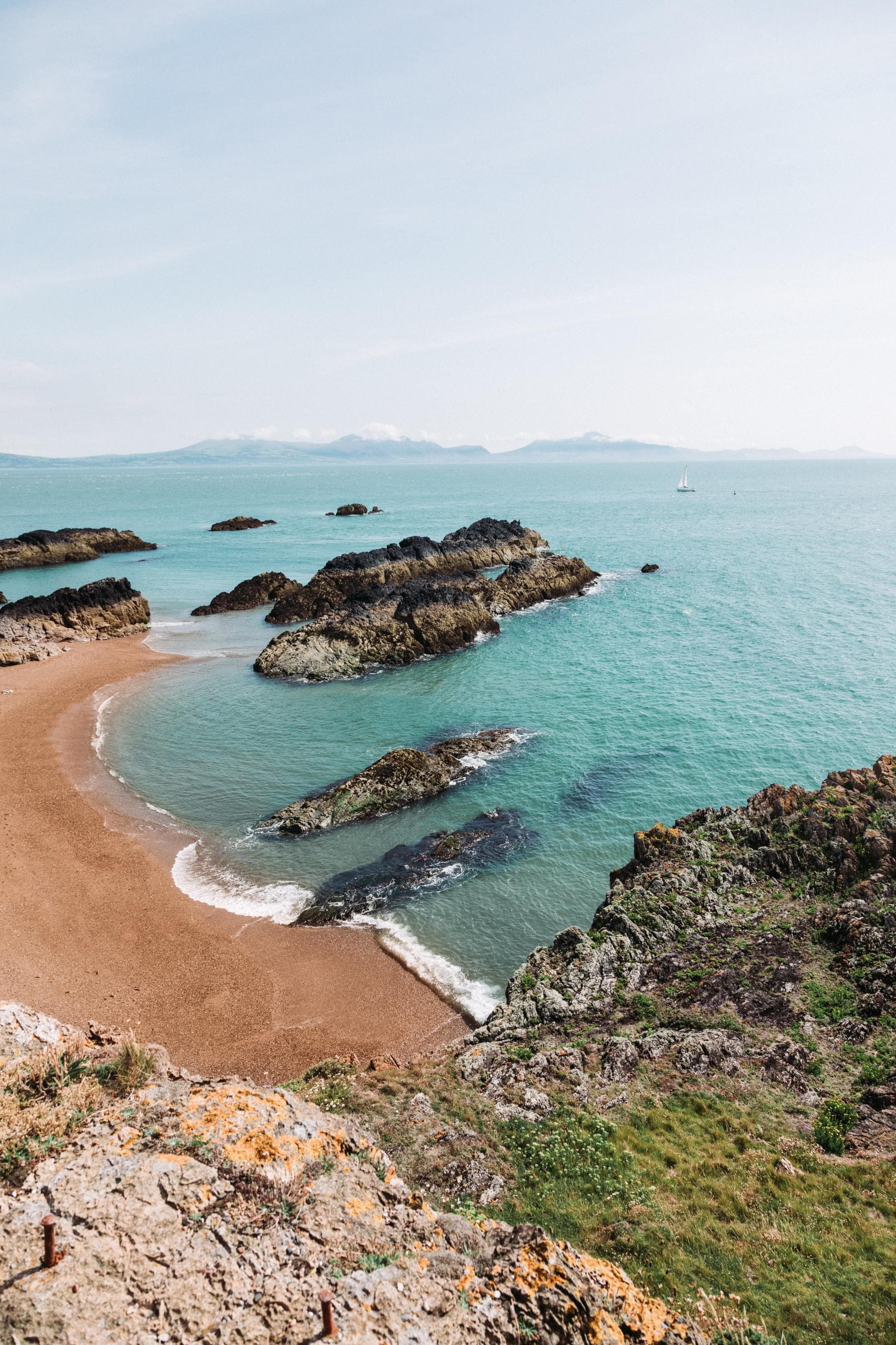 a cliff onto a sand beach and vast ocean on a sunny day
