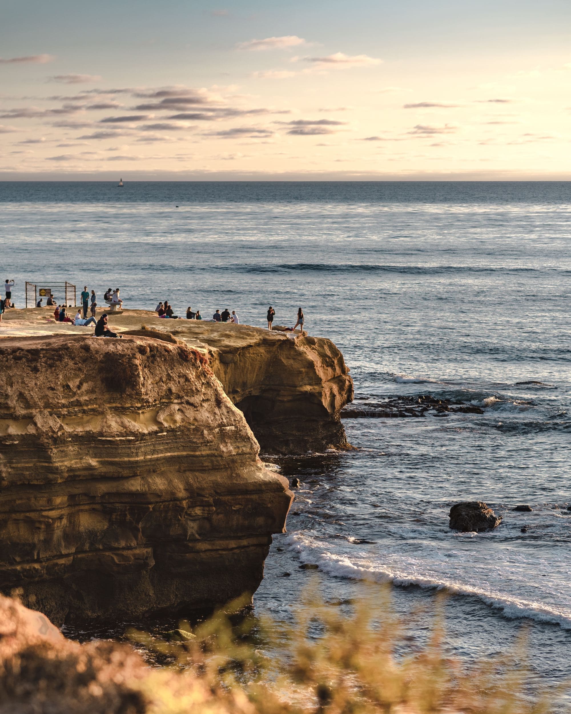 people stand on the cliffs over the ocean at sunset
