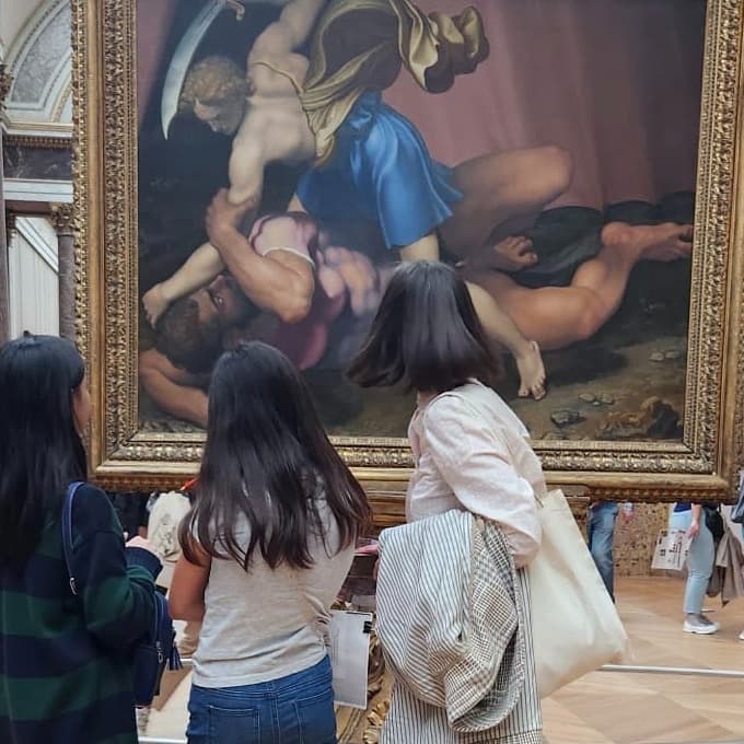 Three women standing in front of a painting.