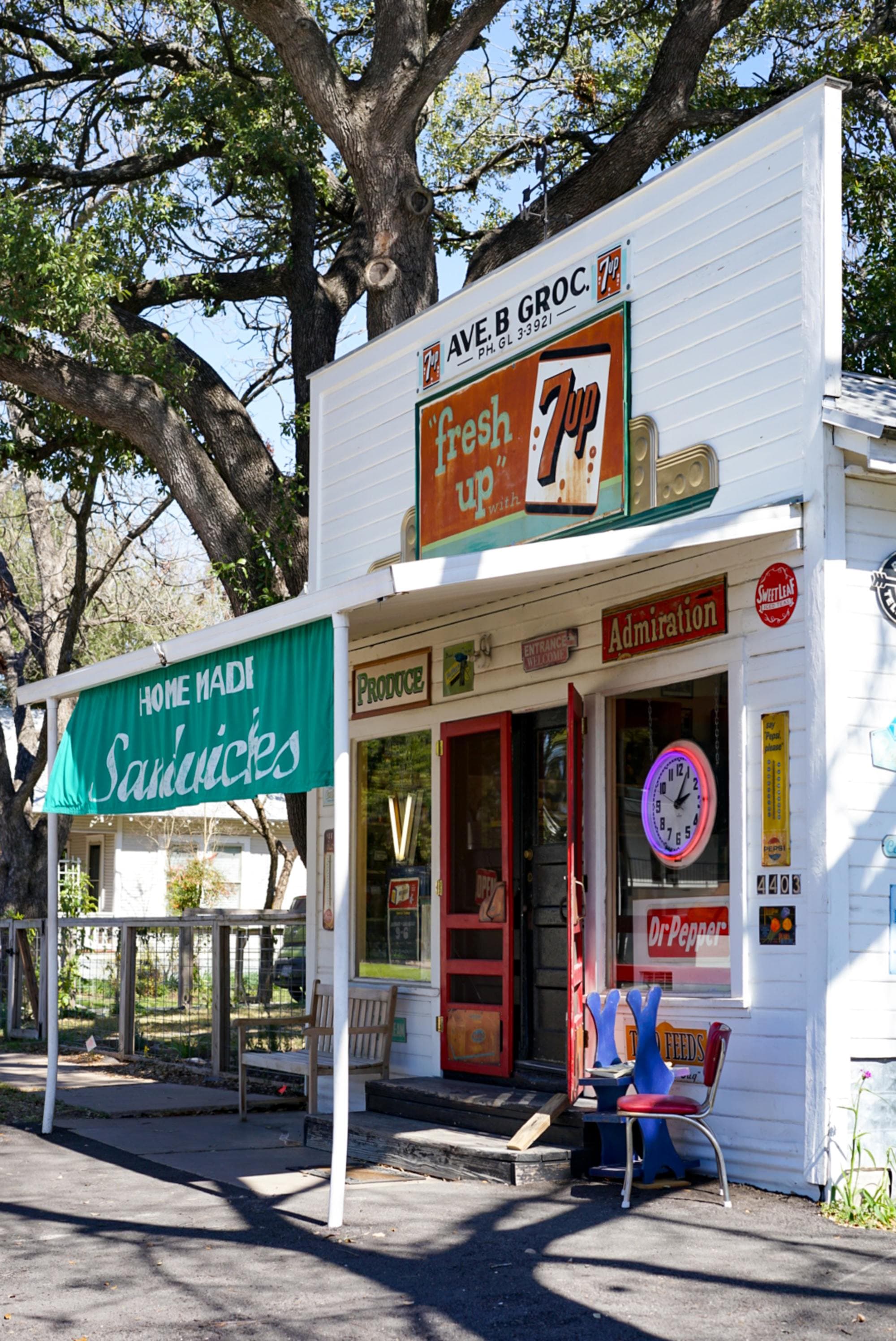 outside of a classic grocery store in a small white building with many signs