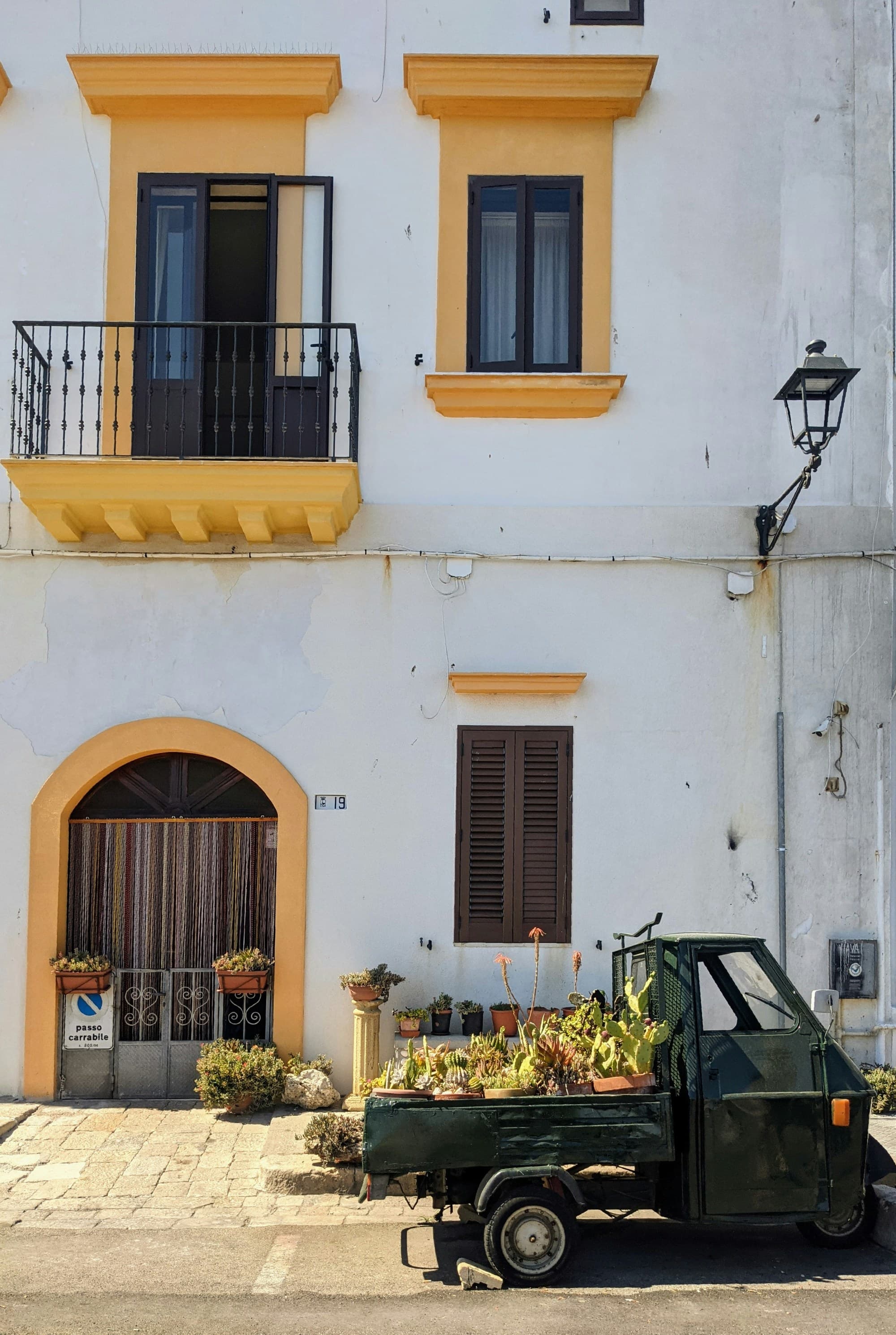 A picture of a green truck parked in front of a white and yellow building.