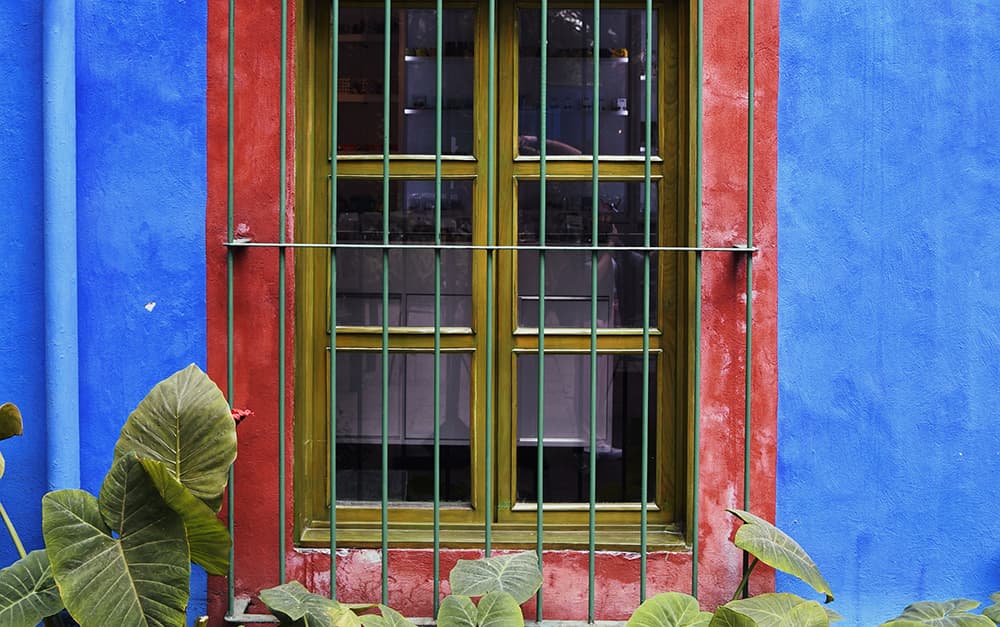 A large window with gold panes on a blue and red house