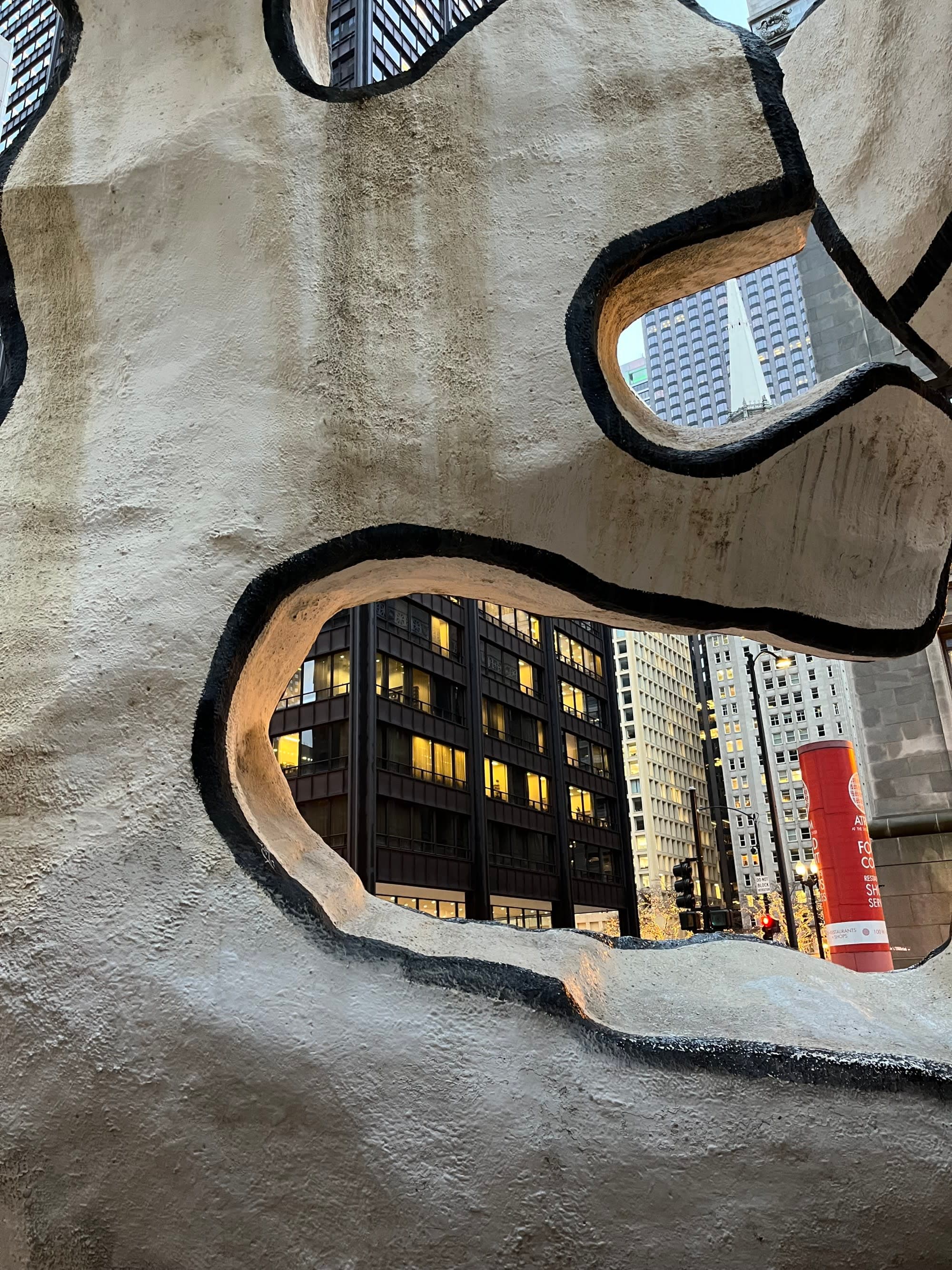 a city seen through an abstract stone-like sculpture