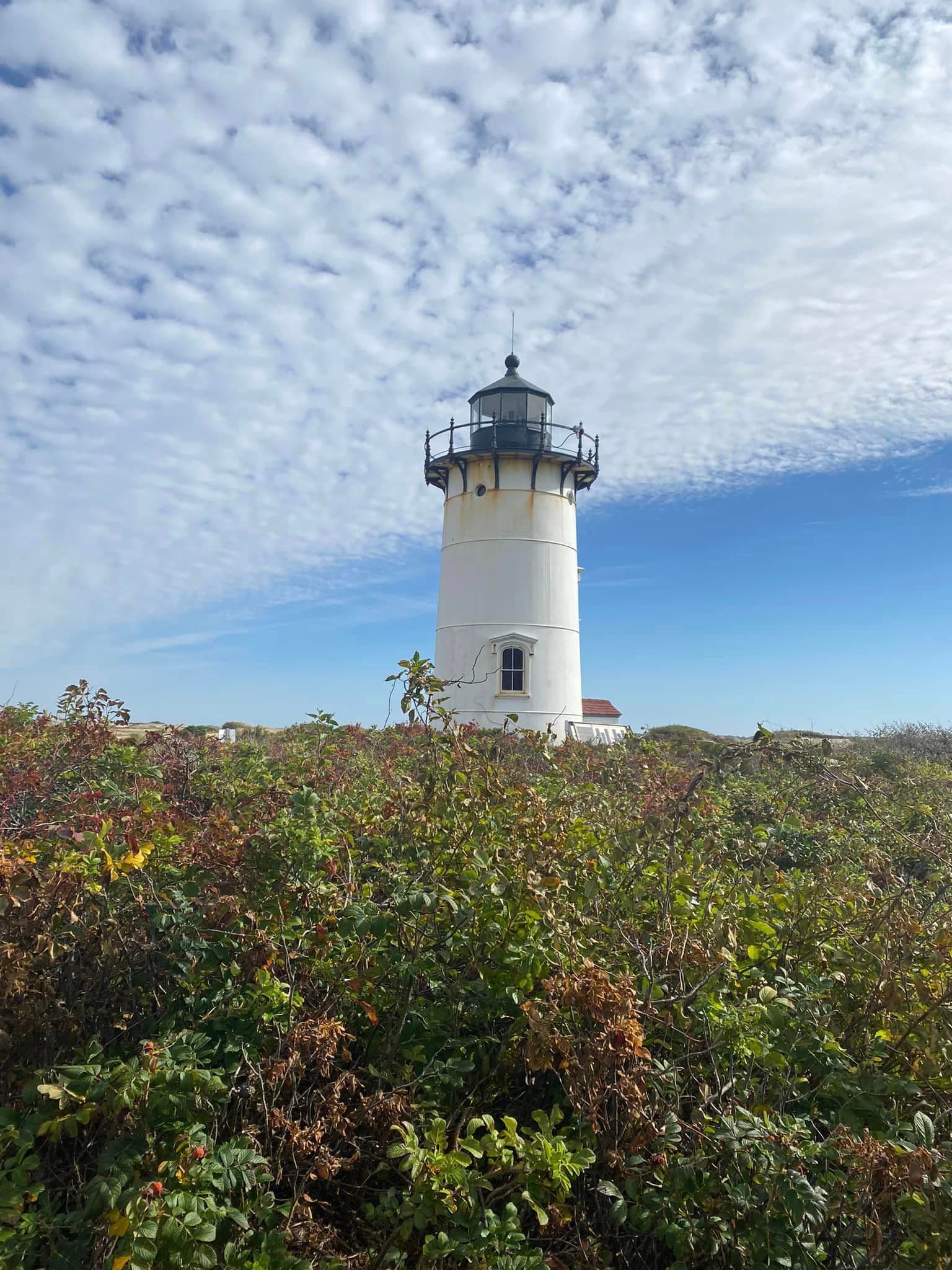 A lighthouse at the top of a grassy hill