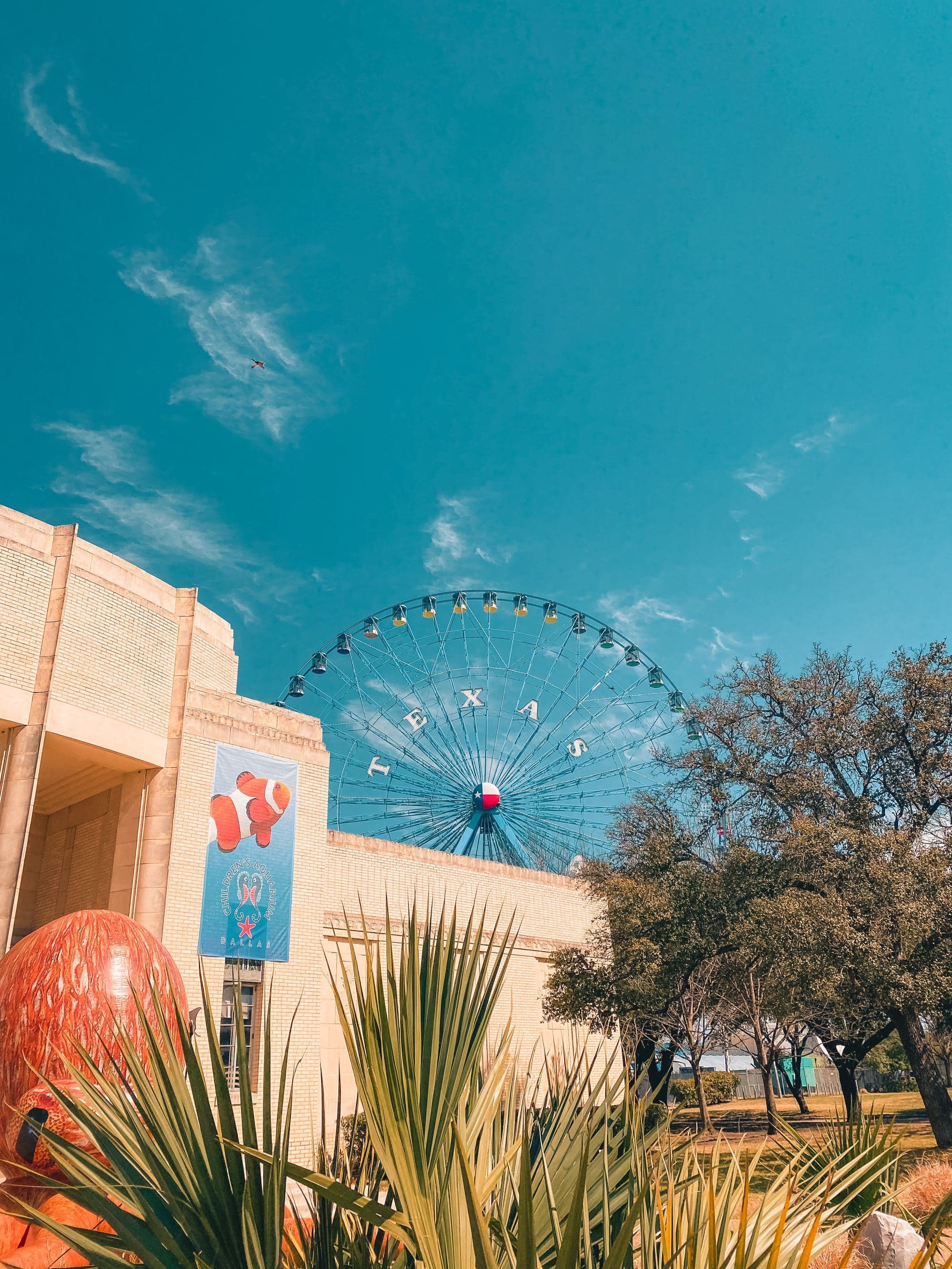 sunny day in a city with a ferris wheel that reads, "Dallas."