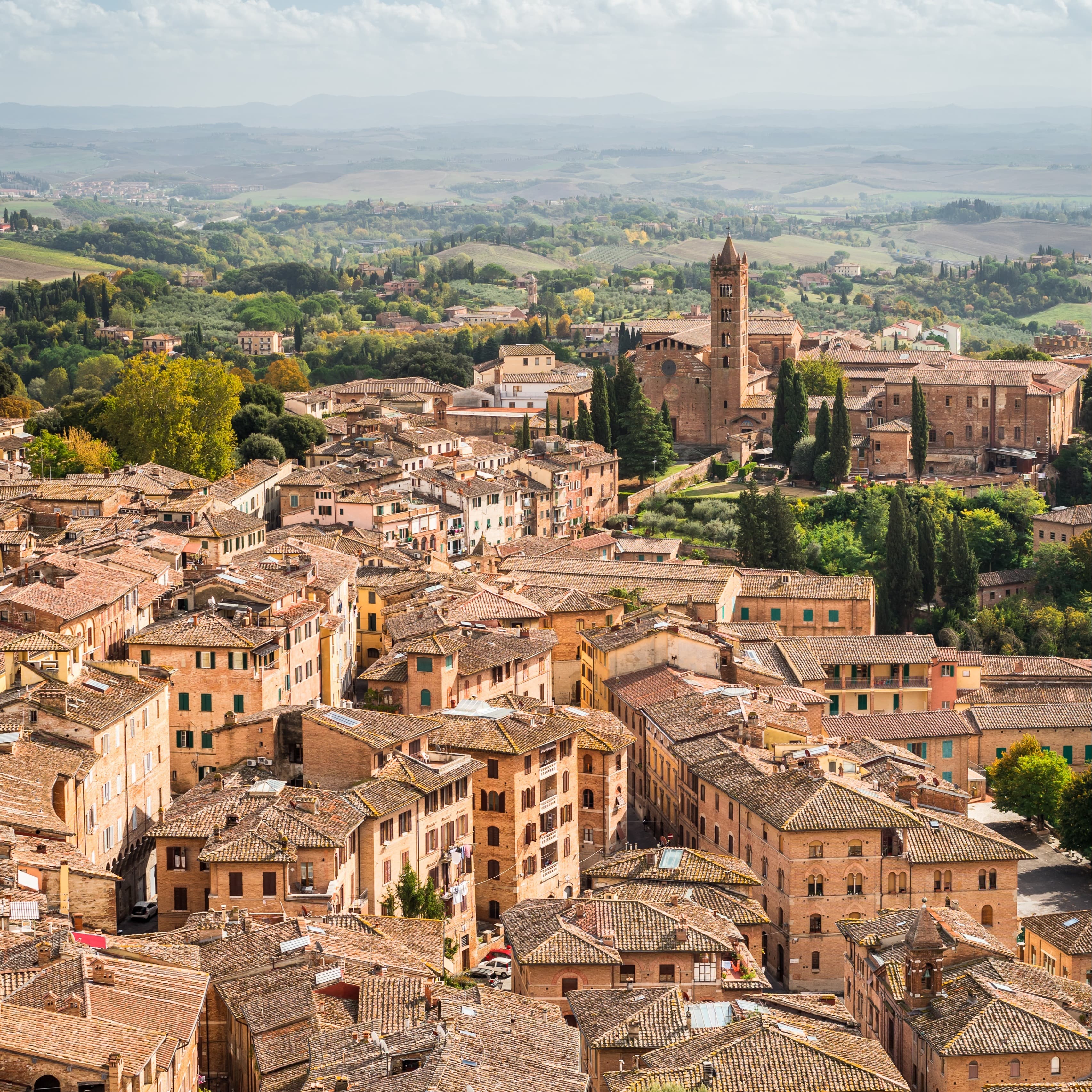 Aerial views of a village surrounded by green fields in Tuscany.