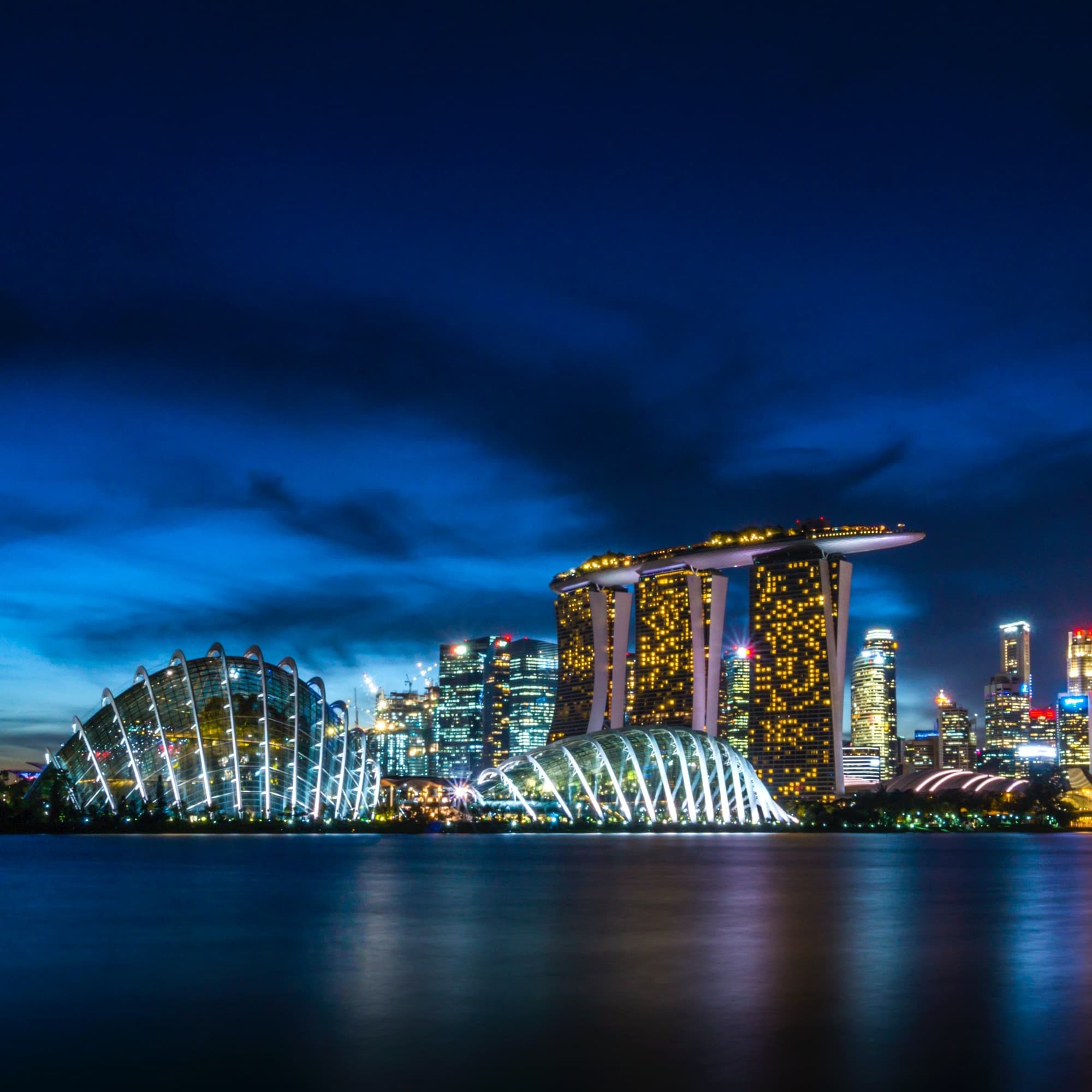City skyline of Singapore at night with bright lights and a beautiful view of the water.