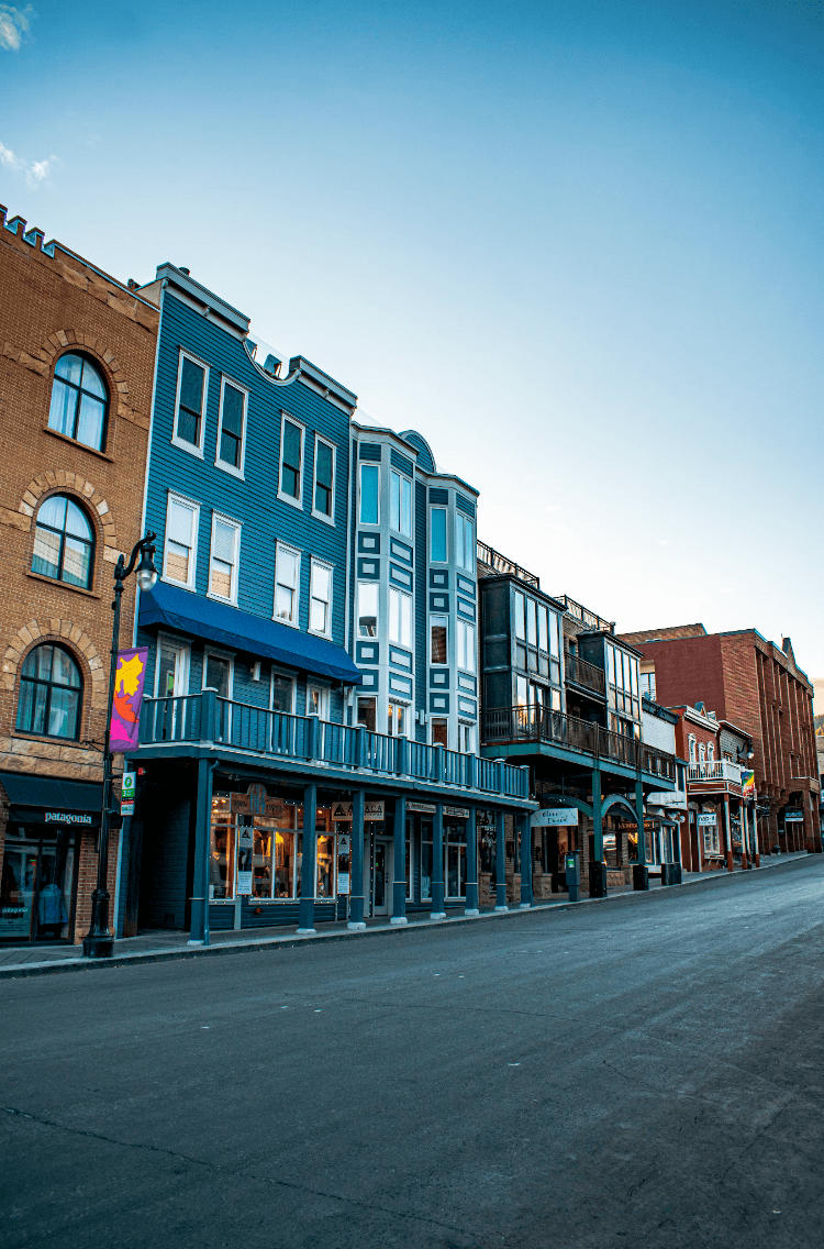 An empty street view of colorful, multiple story buildings and storefronts.
