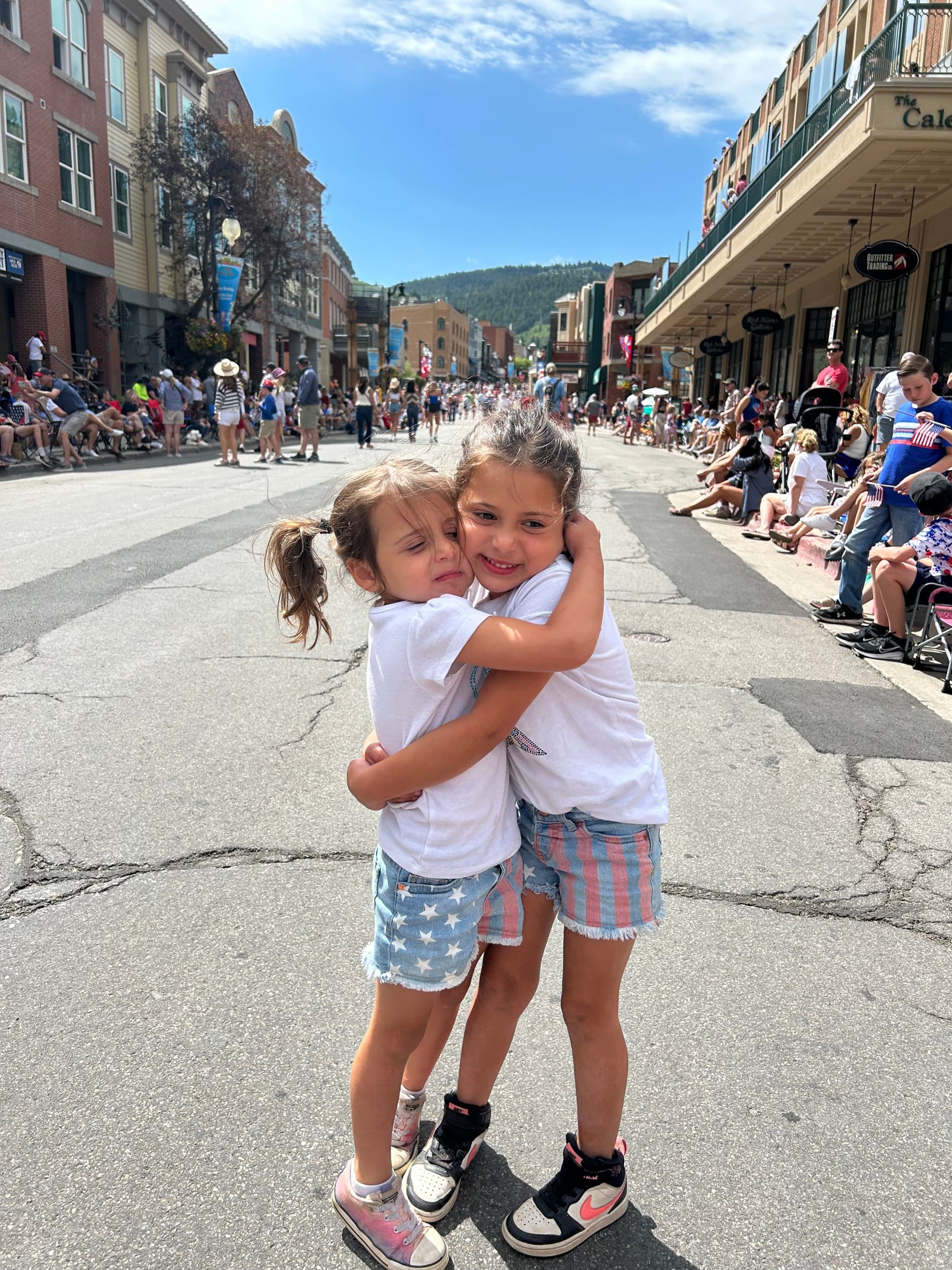 Two kids hugging each other on a street.