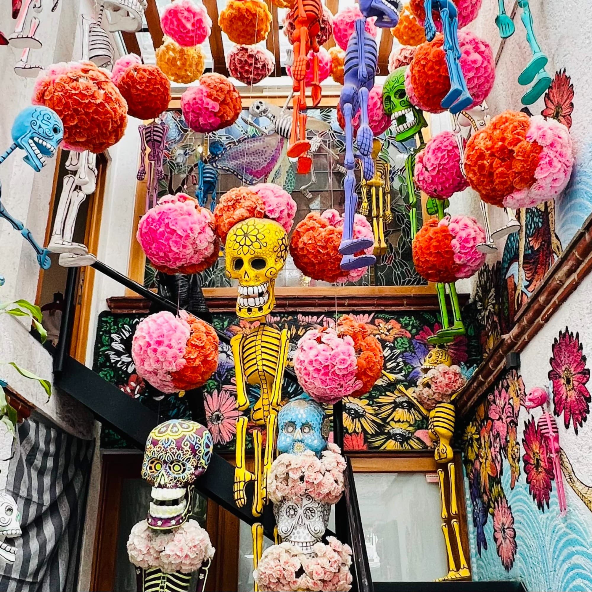 Painted skeletons hanging with other colorful decoration in a street.