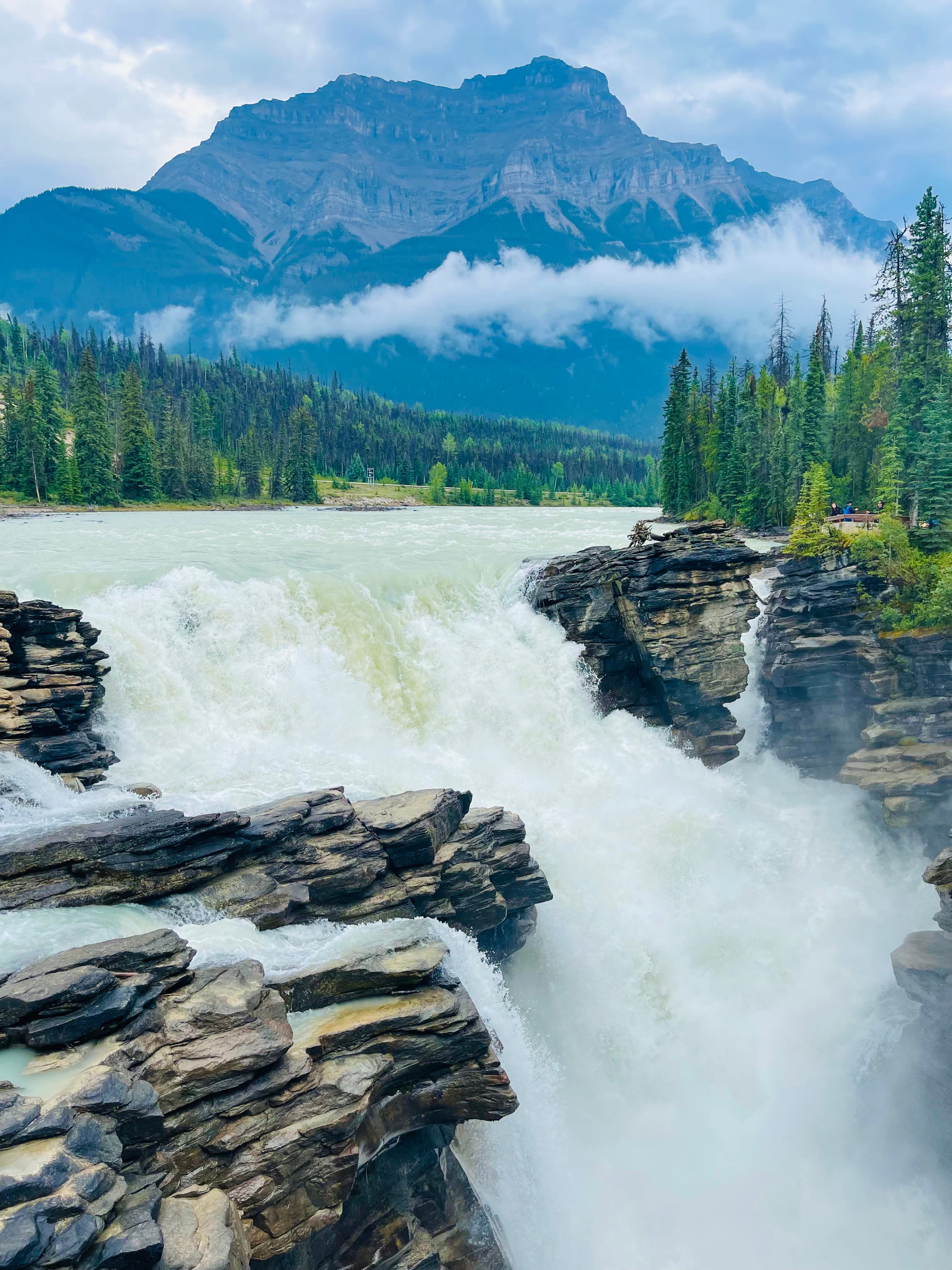 A picture of waterfalls flanked by rocks and a mountain in the background.