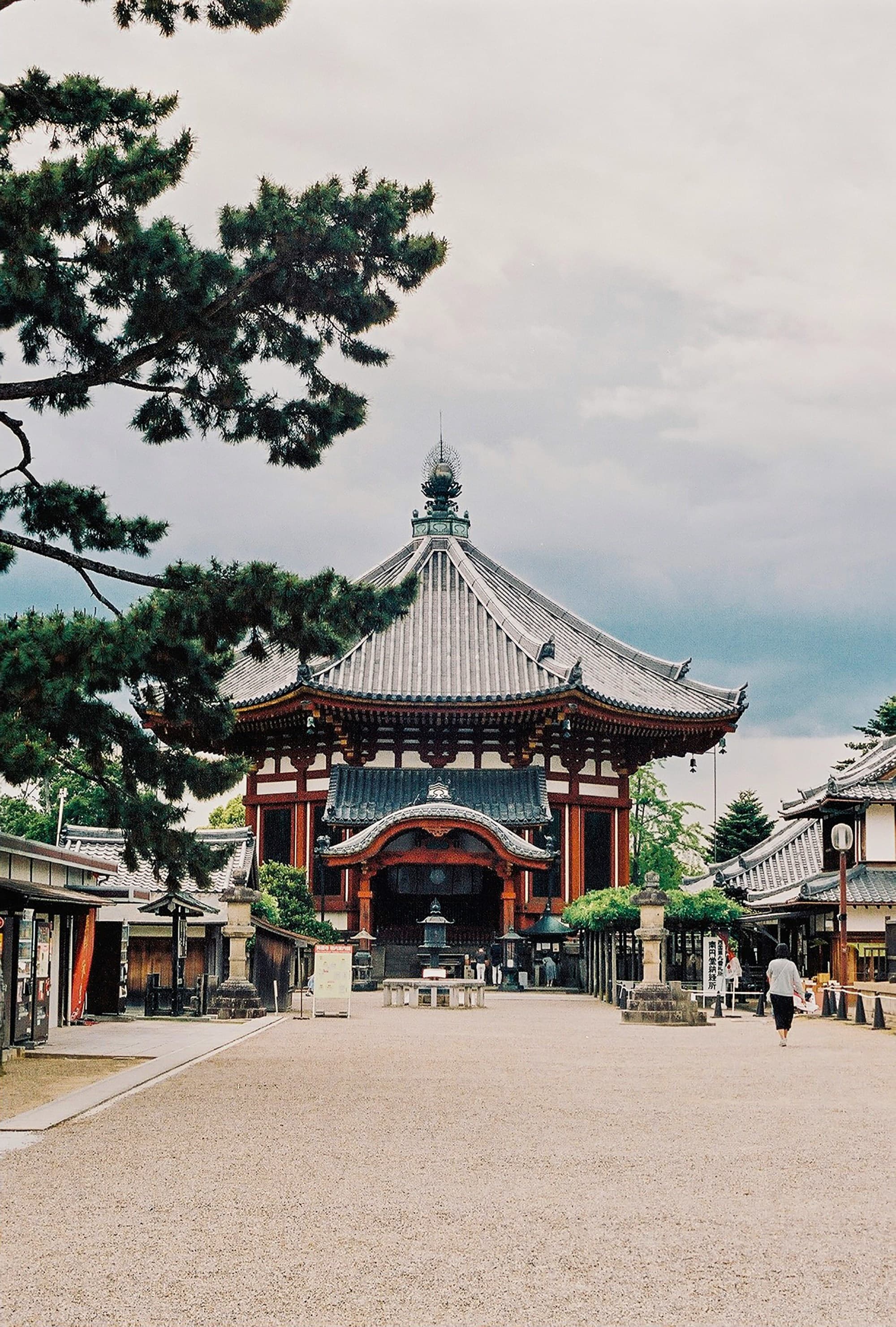 A view of a beautiful temple in Japan surrounded by trees and a cloudy sky.