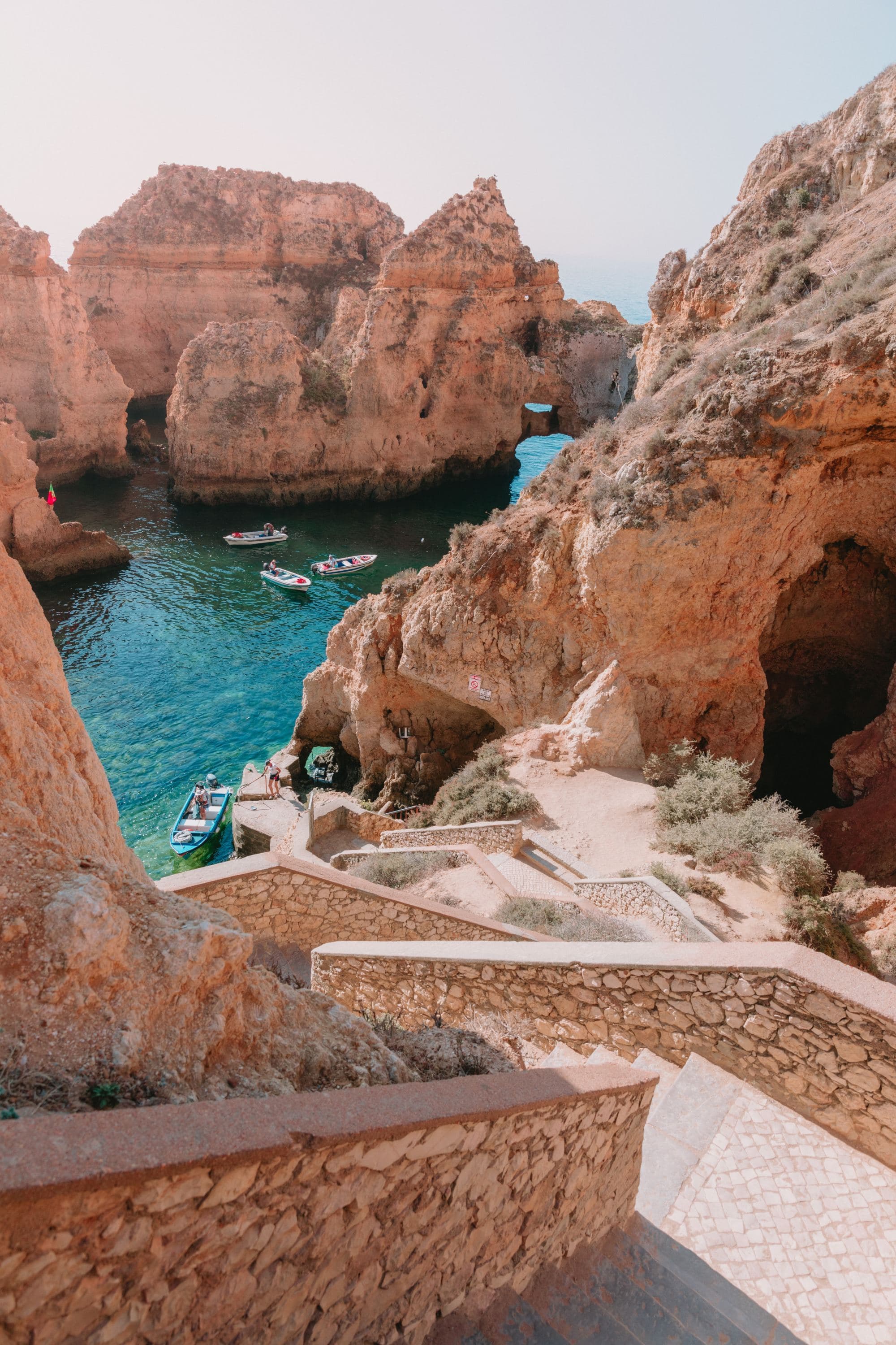 Three boats in a body of water between rocks.