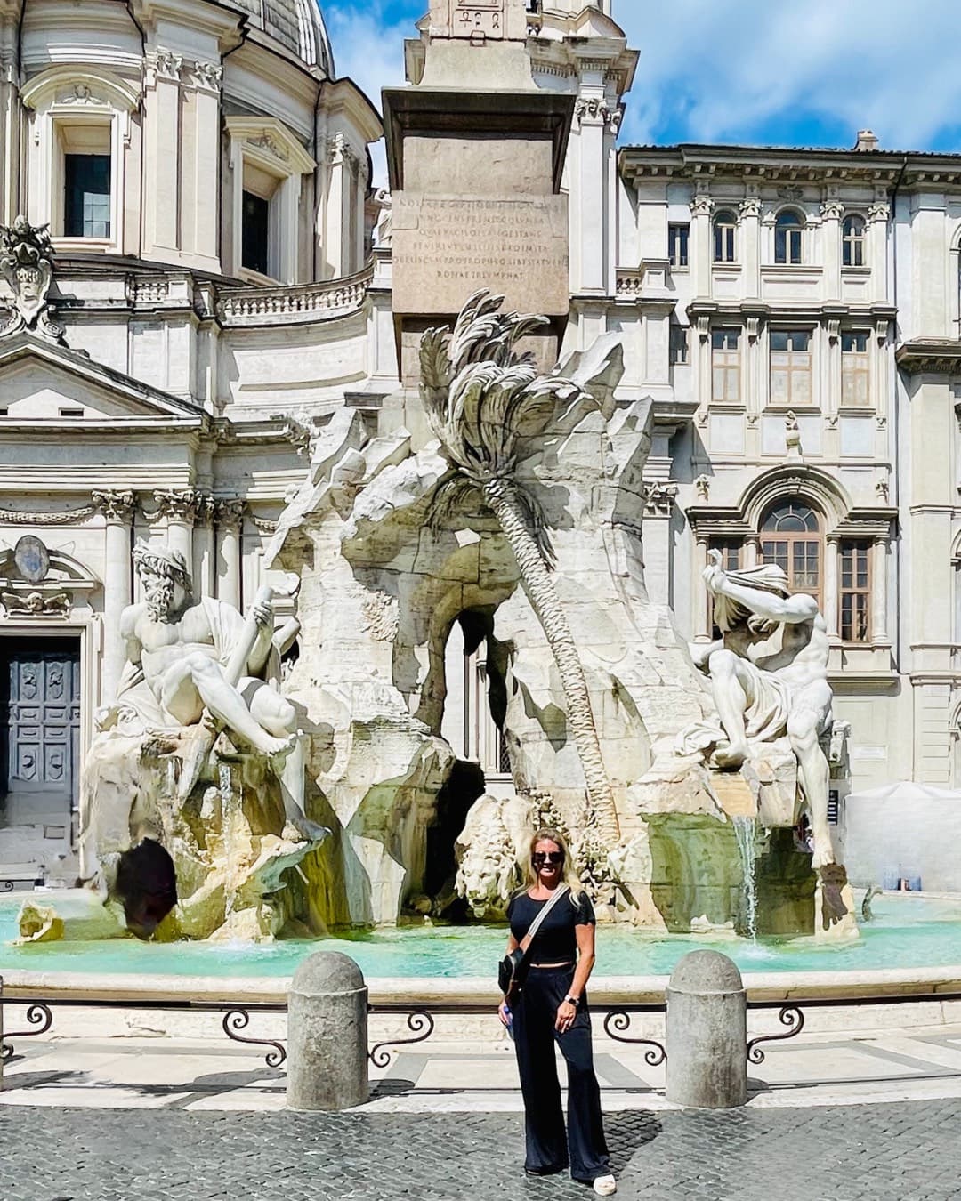 Woman in black clothes in front of a fountain.